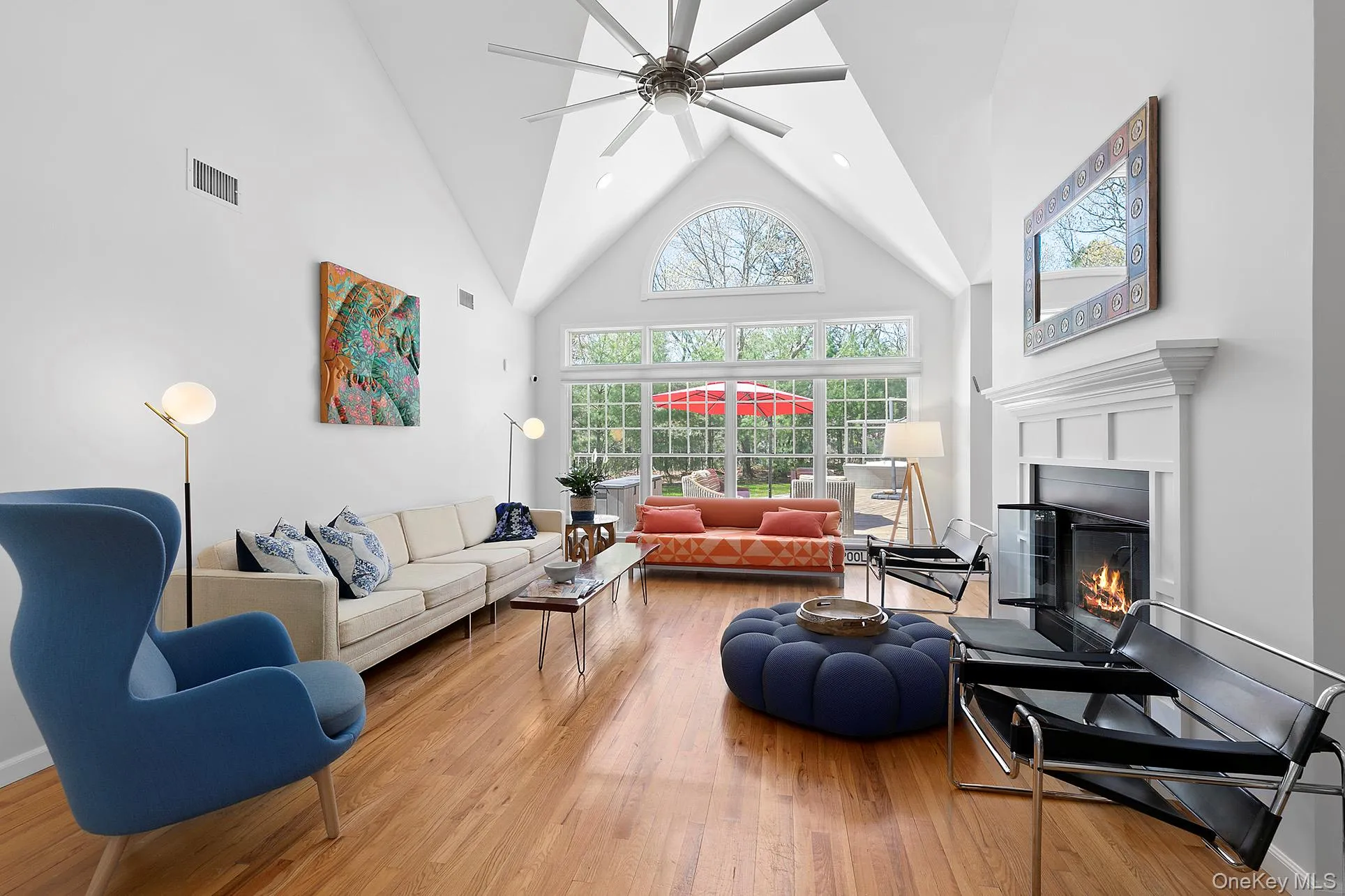 Living area featuring high vaulted ceiling, wood finished floors, a glass covered fireplace, ceiling fan, and recessed lighting Living area featuring high vaulted ceiling, wood finished floors, a glass covered fireplace, ceiling fan, and recessed lighting