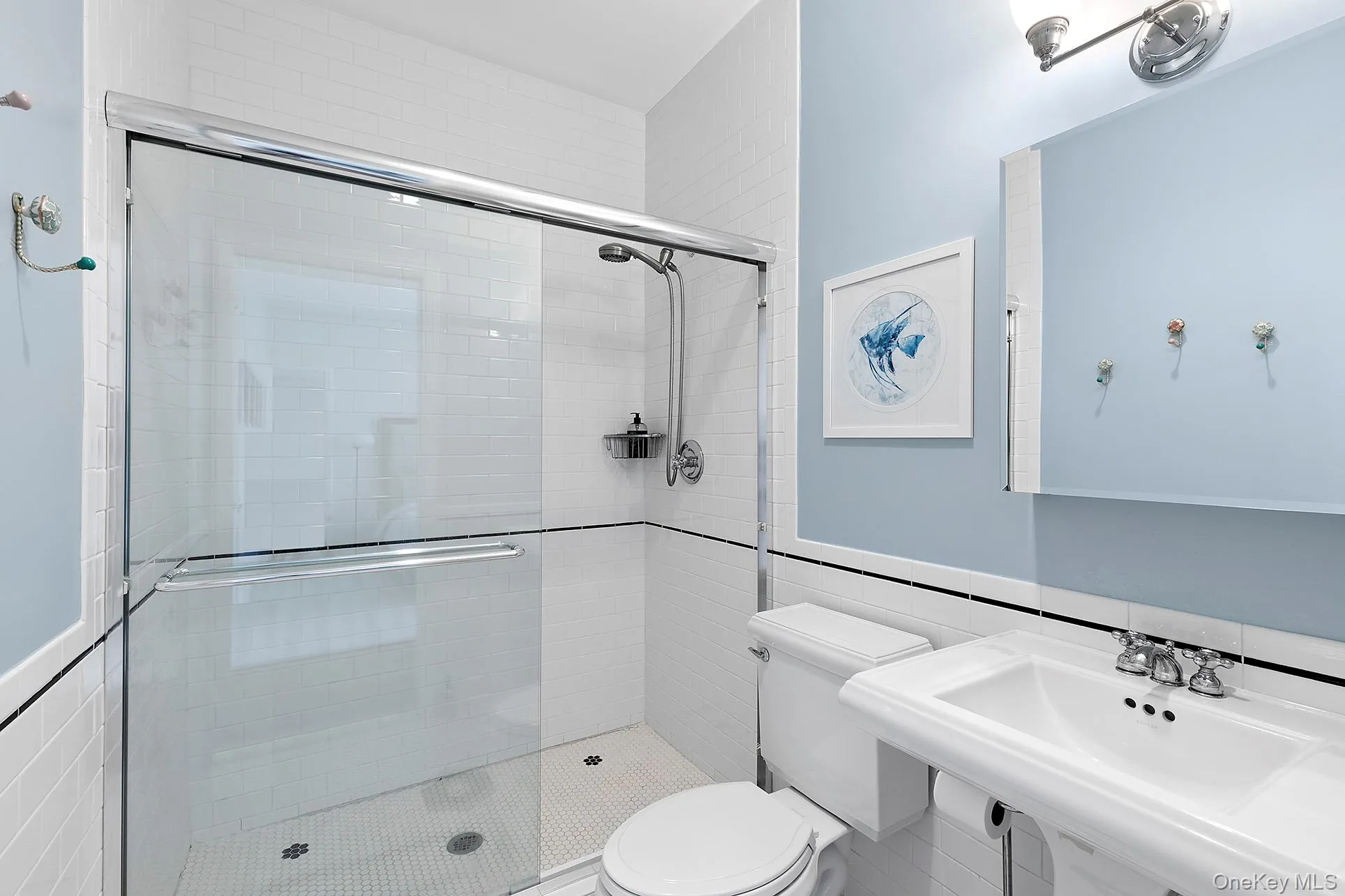 Bathroom featuring tile walls, a shower stall, and a wainscoted wall Bathroom featuring tile walls, a shower stall, and a wainscoted wall