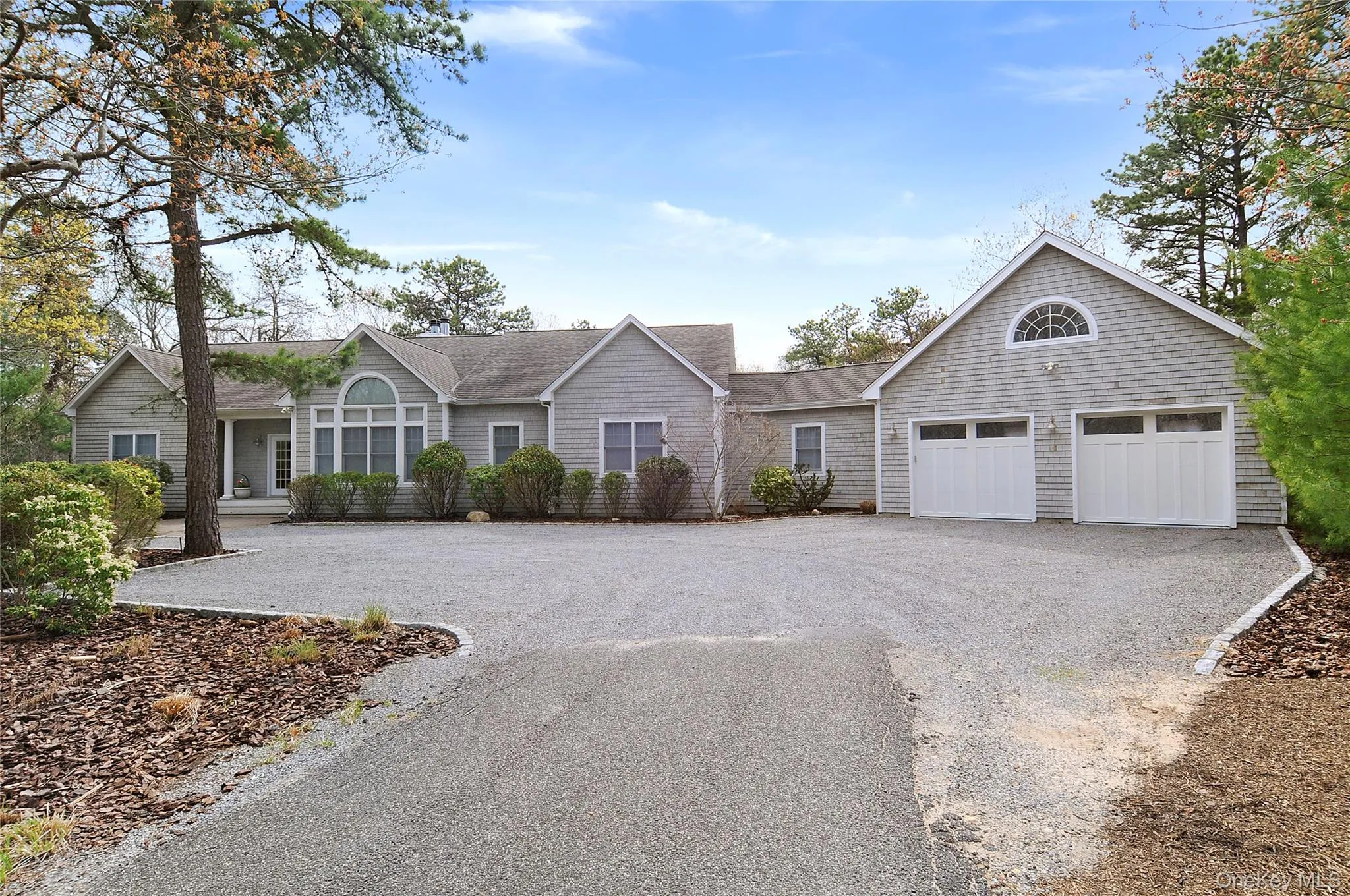 Single story home featuring a shingled roof and asphalt driveway Single story home featuring a shingled roof and asphalt driveway
