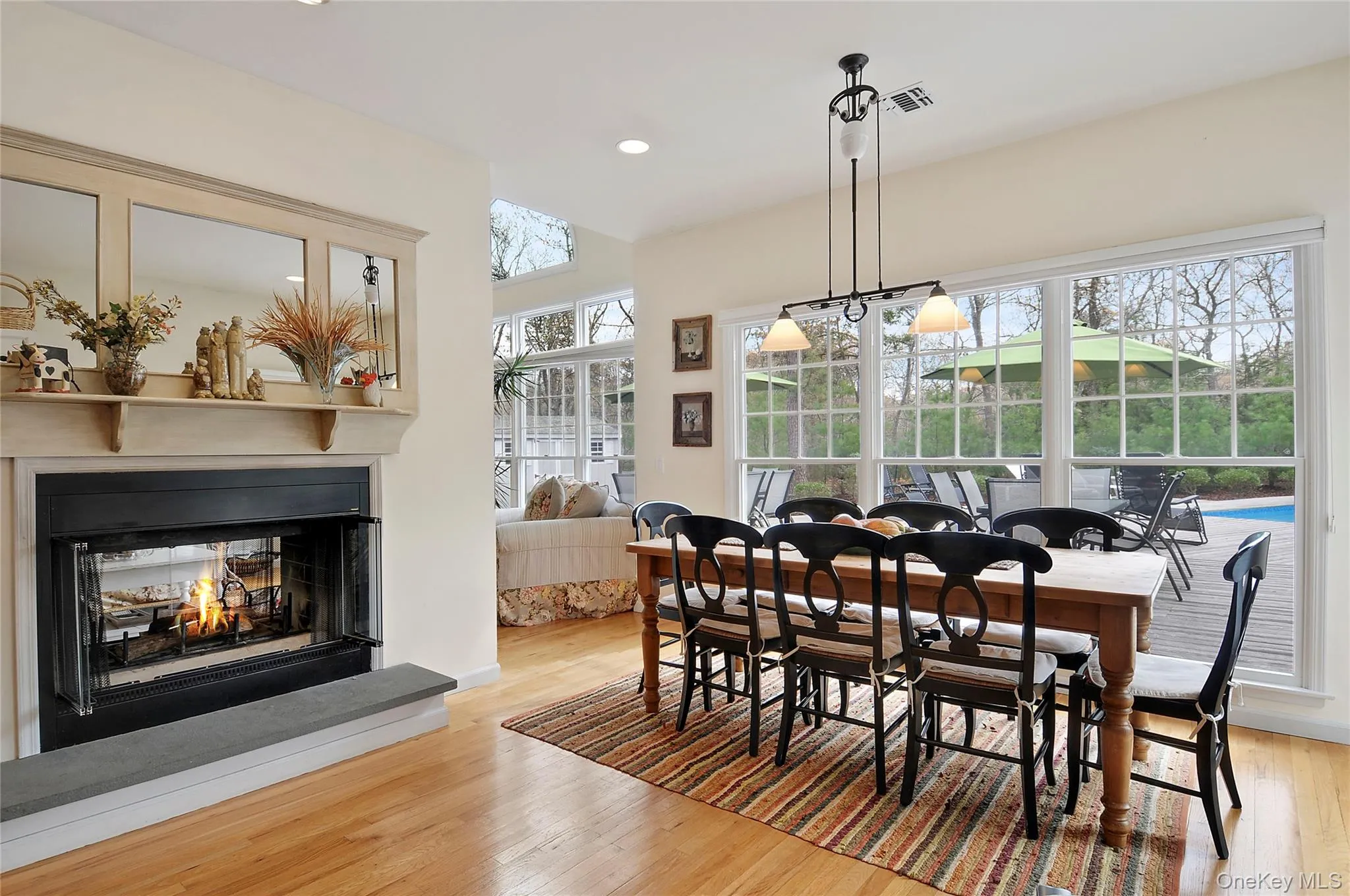 Dining room featuring light wood-type flooring, recessed lighting, and a multi sided fireplace Dining room featuring light wood-type flooring, recessed lighting, and a multi sided fireplace
