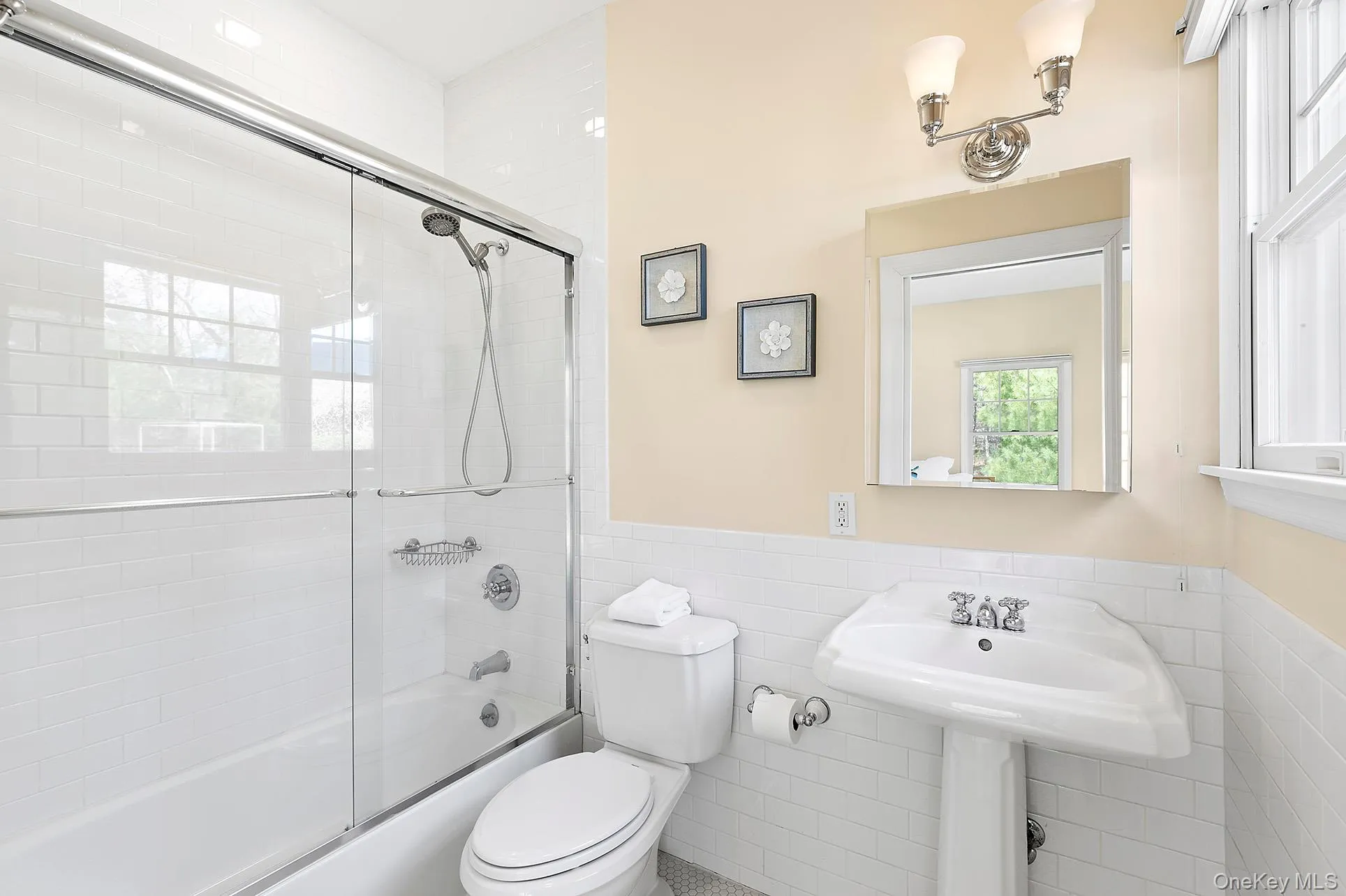 Full bathroom with combined bath / shower with glass door, tile walls, and a wainscoted wall Full bathroom with combined bath / shower with glass door, tile walls, and a wainscoted wall