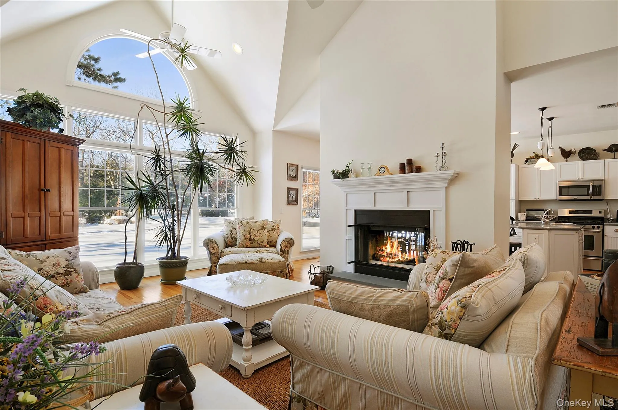 Living area featuring high vaulted ceiling, wood finished floors, and a glass covered fireplace Living area featuring high vaulted ceiling, wood finished floors, and a glass covered fireplace