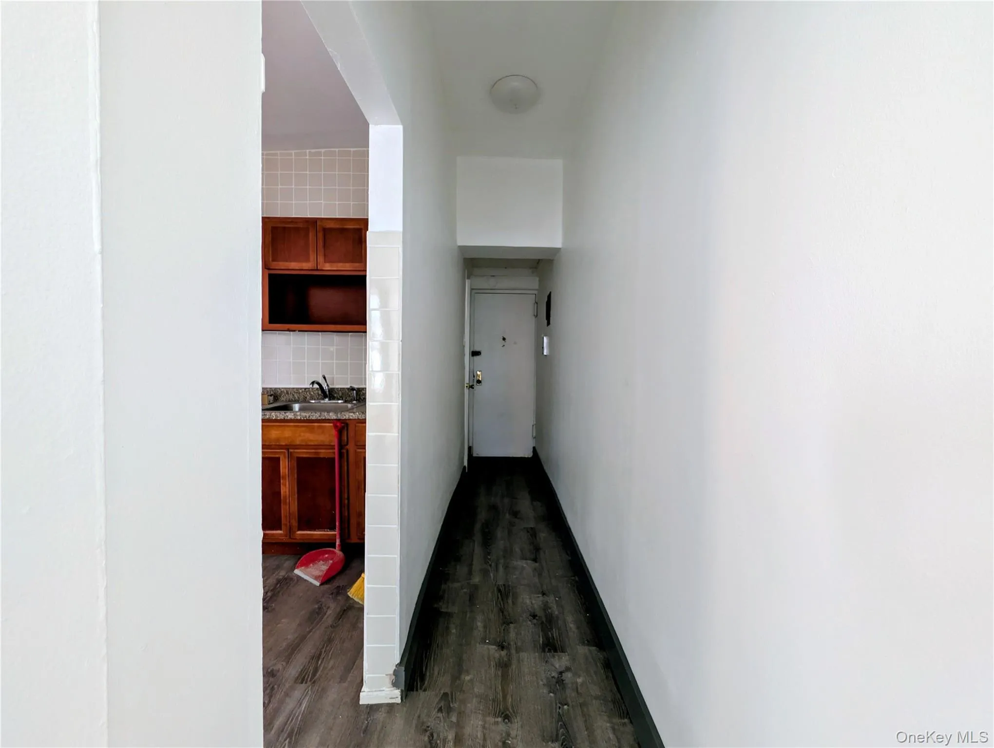 Hallway featuring dark wood-style floors and a sink Hallway featuring dark wood-style floors and a sink