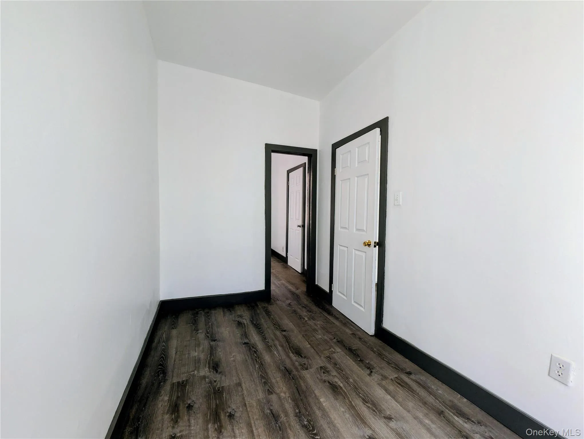 Empty room featuring dark wood-type flooring and baseboards Empty room featuring dark wood-type flooring and baseboards