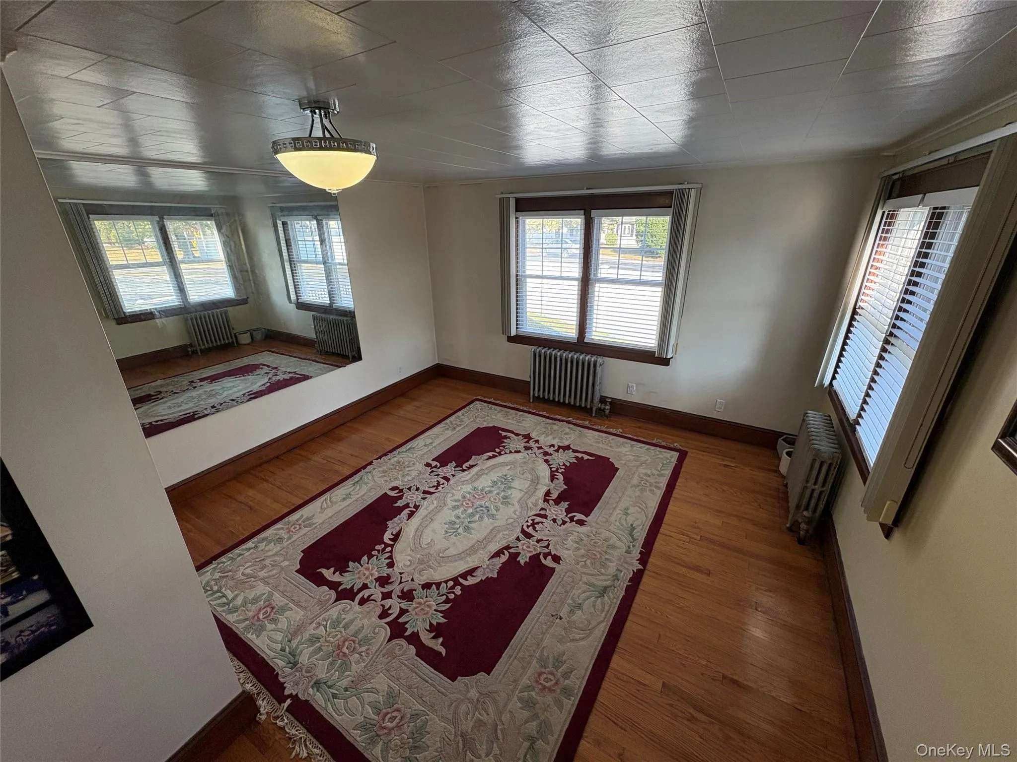 Living room with wood finished floors, radiator heating unit, and plenty of natural light Living room with wood finished floors, radiator heating unit, and plenty of natural light
