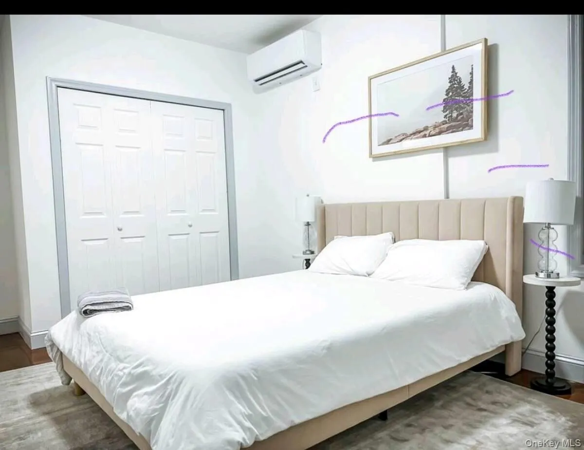 Bedroom featuring wood finished floors, an AC wall unit, and a closet Bedroom featuring wood finished floors, an AC wall unit, and a closet