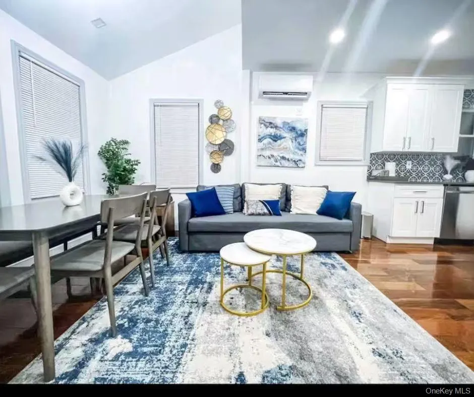 Living room featuring vaulted ceiling, dark wood finished floors, and a wall mounted air conditioner Living room featuring vaulted ceiling, dark wood finished floors, and a wall mounted air conditioner
