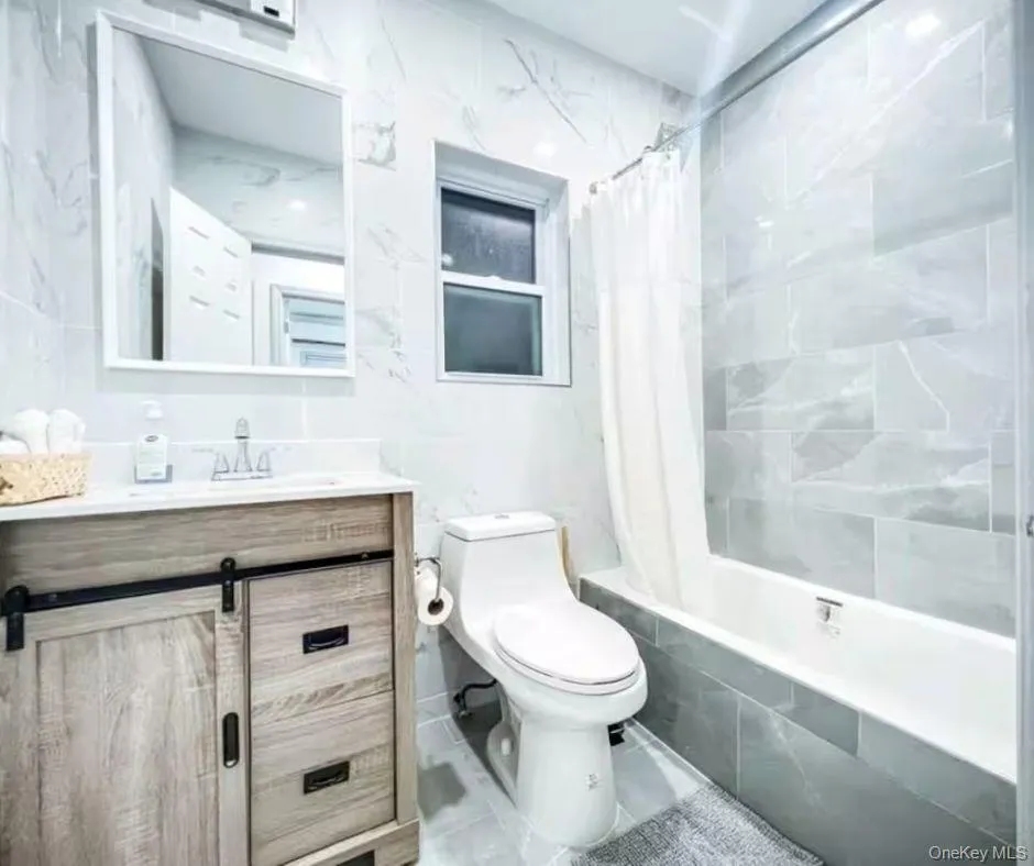 Bathroom featuring tiled shower / bath combo, tile walls, and vanity Bathroom featuring tiled shower / bath combo, tile walls, and vanity