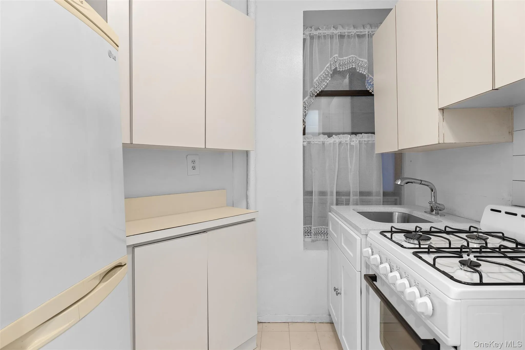 Kitchen featuring white appliances, light countertops, and light tile patterned floors Kitchen featuring white appliances, light countertops, and light tile patterned floors