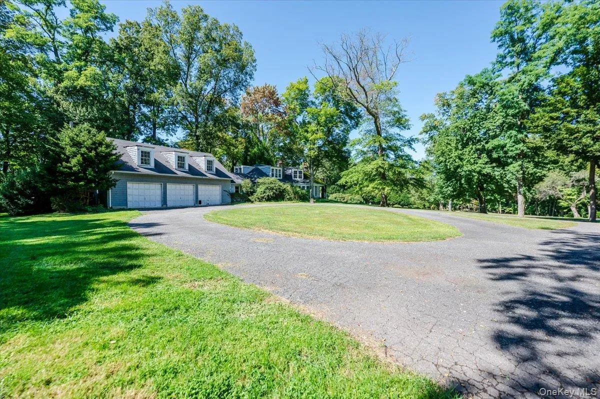 View of front of home featuring a garage, asphalt driveway, a front yard, and view of wooded area View of front of home featuring a garage, asphalt driveway, a front yard, and view of wooded area