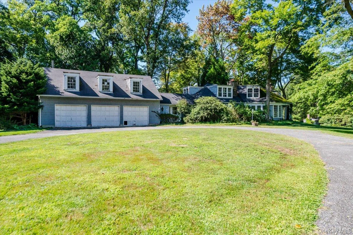 Cape cod-style house with asphalt driveway, view of scattered trees, and a front yard Cape cod-style house with asphalt driveway, view of scattered trees, and a front yard