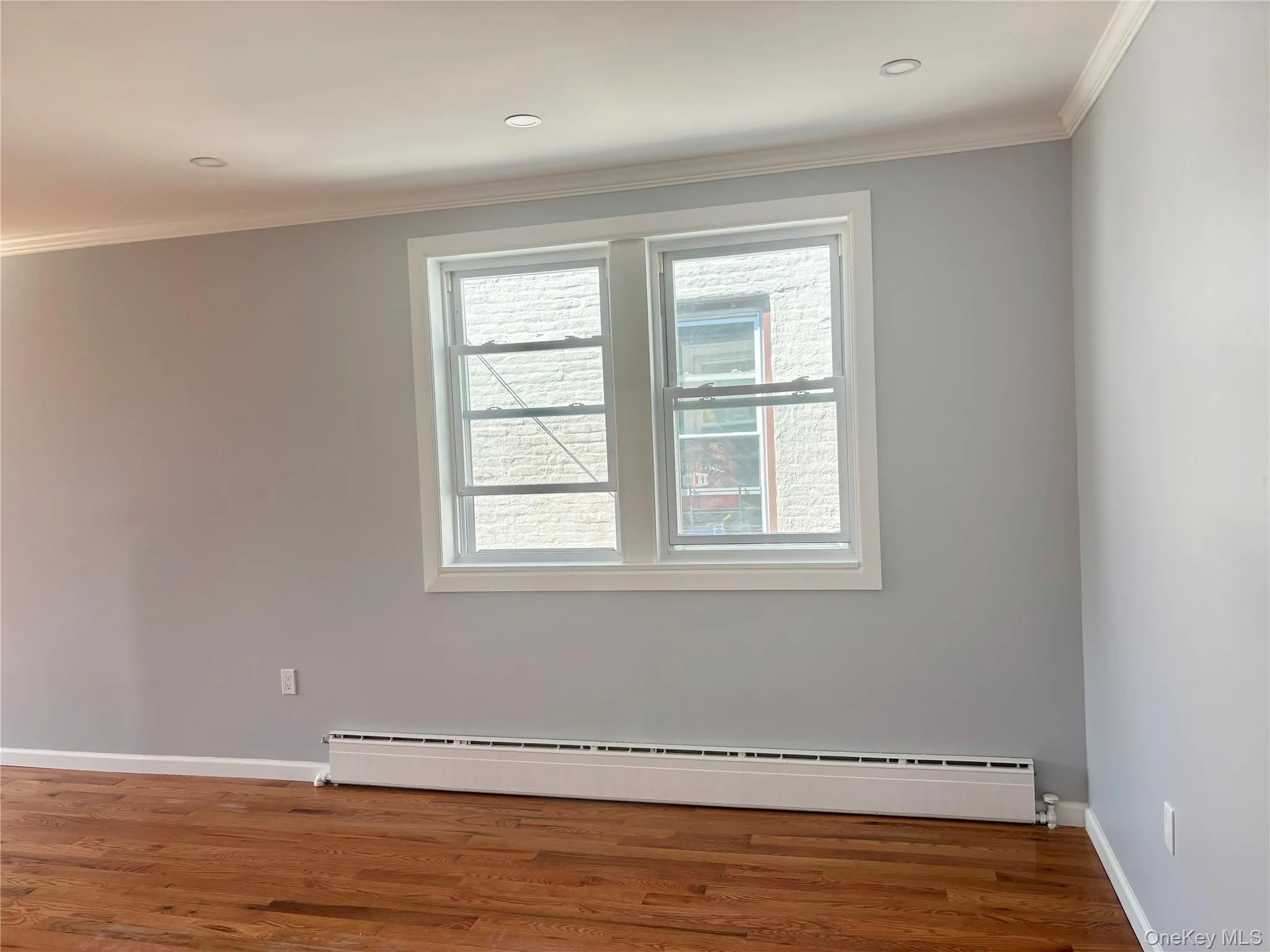 Unfurnished room with crown molding, baseboard heating, dark wood-type flooring, and recessed lighting Unfurnished room with crown molding, baseboard heating, dark wood-type flooring, and recessed lighting