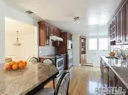 Kitchen featuring a breakfast bar area, light wood-style flooring, appliances with stainless steel finishes, and dark stone countertops Kitchen featuring a breakfast bar area, light wood-style flooring, appliances with stainless steel finishes, and dark stone countertops