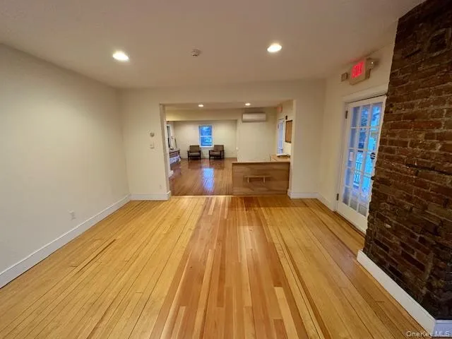 Spare room featuring light wood-style flooring, recessed lighting, and a wall mounted air conditioner Spare room featuring light wood-style flooring, recessed lighting, and a wall mounted air conditioner