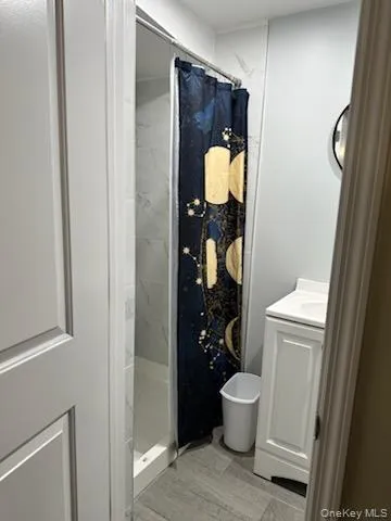 Bathroom with a marble finish shower, vanity, and light wood finished floors Bathroom with a marble finish shower, vanity, and light wood finished floors