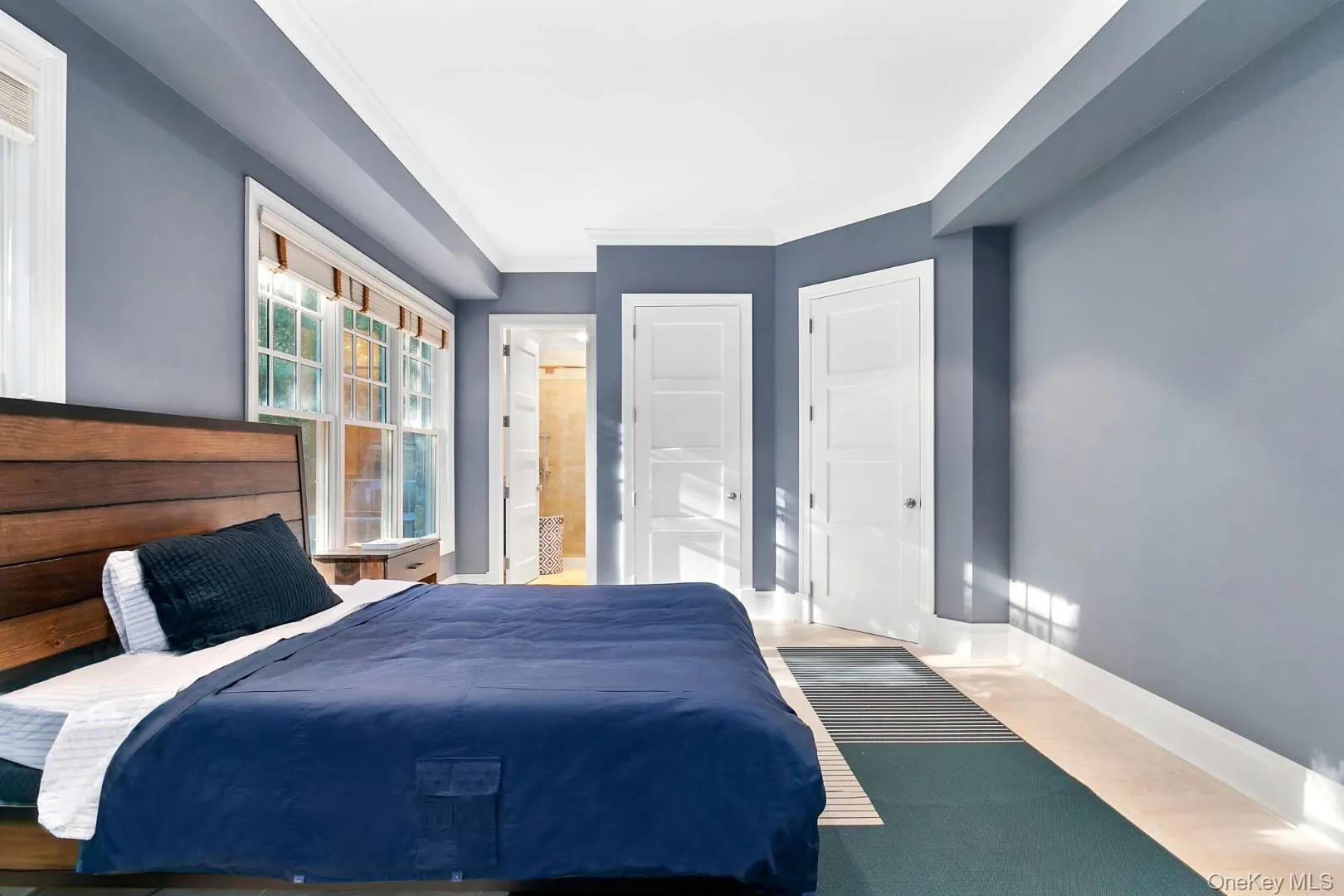 Bedroom featuring ornamental molding, ensuite bath, a closet, and wood finished floors Bedroom featuring ornamental molding, ensuite bath, a closet, and wood finished floors