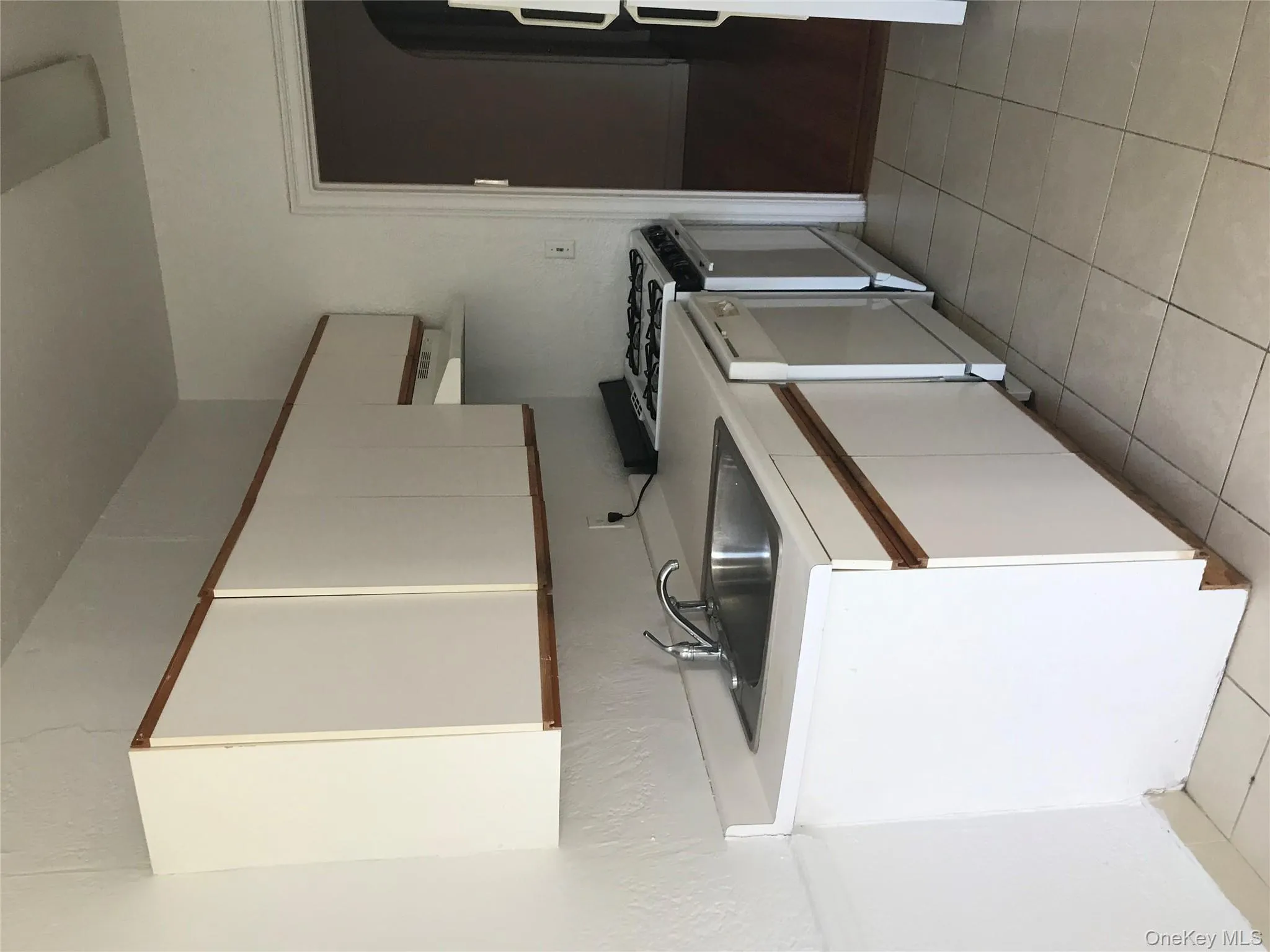 Kitchen with white cabinets, light countertops, light tile patterned floors, and white appliances Kitchen with white cabinets, light countertops, light tile patterned floors, and white appliances