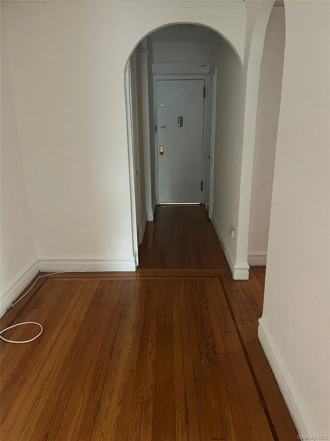 Hall featuring dark wood-style flooring and arched walkways Hall featuring dark wood-style flooring and arched walkways