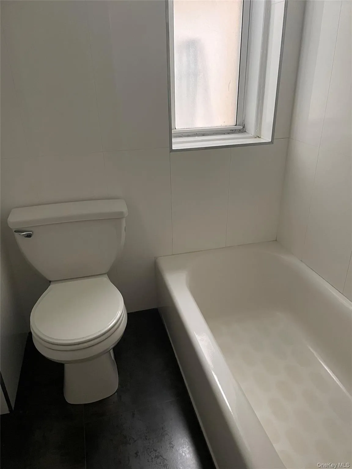 Full bath with toilet and dark tile patterned flooring Full bath with toilet and dark tile patterned flooring