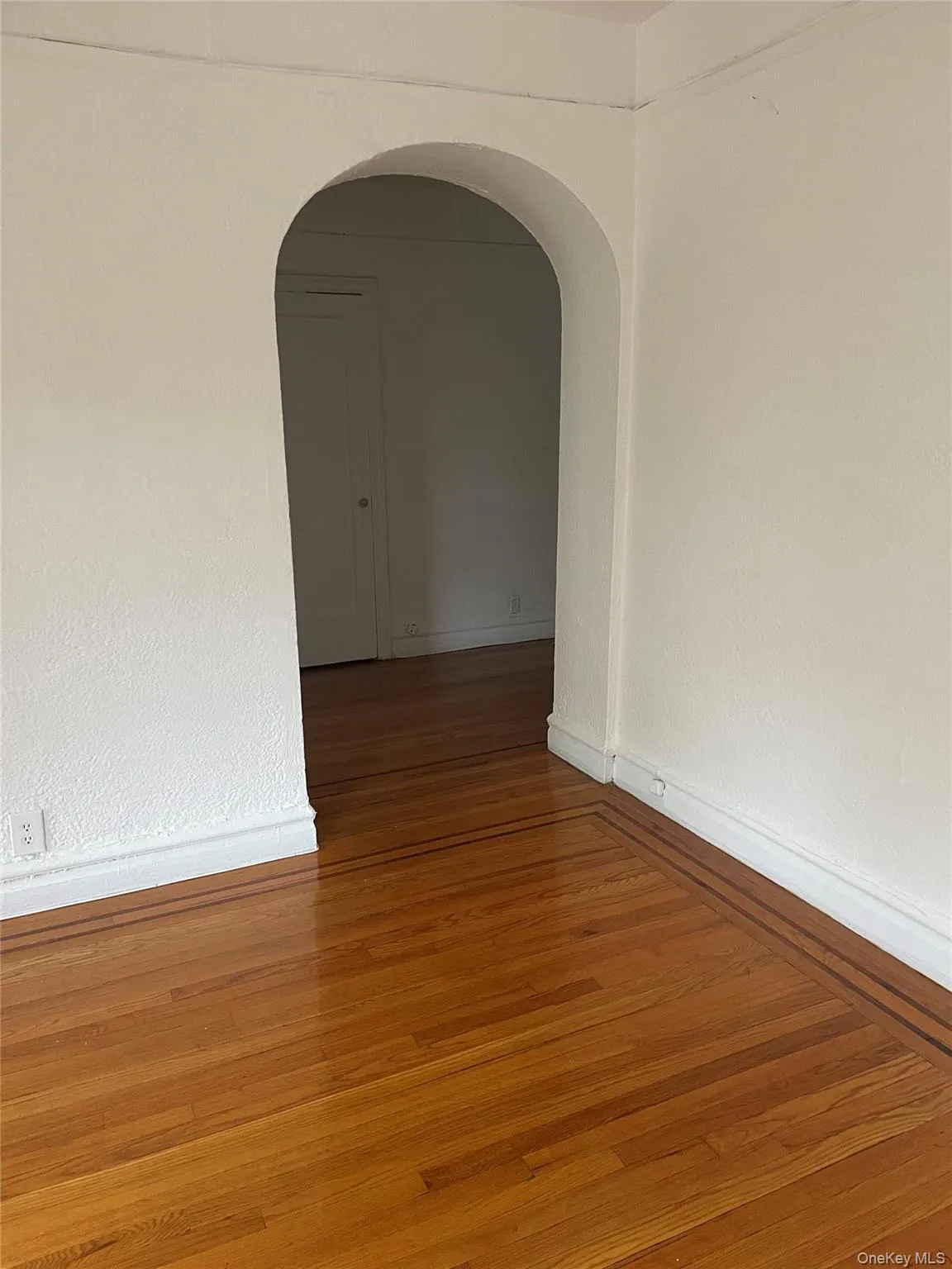 Spare room featuring wood finished floors and arched walkways Spare room featuring wood finished floors and arched walkways