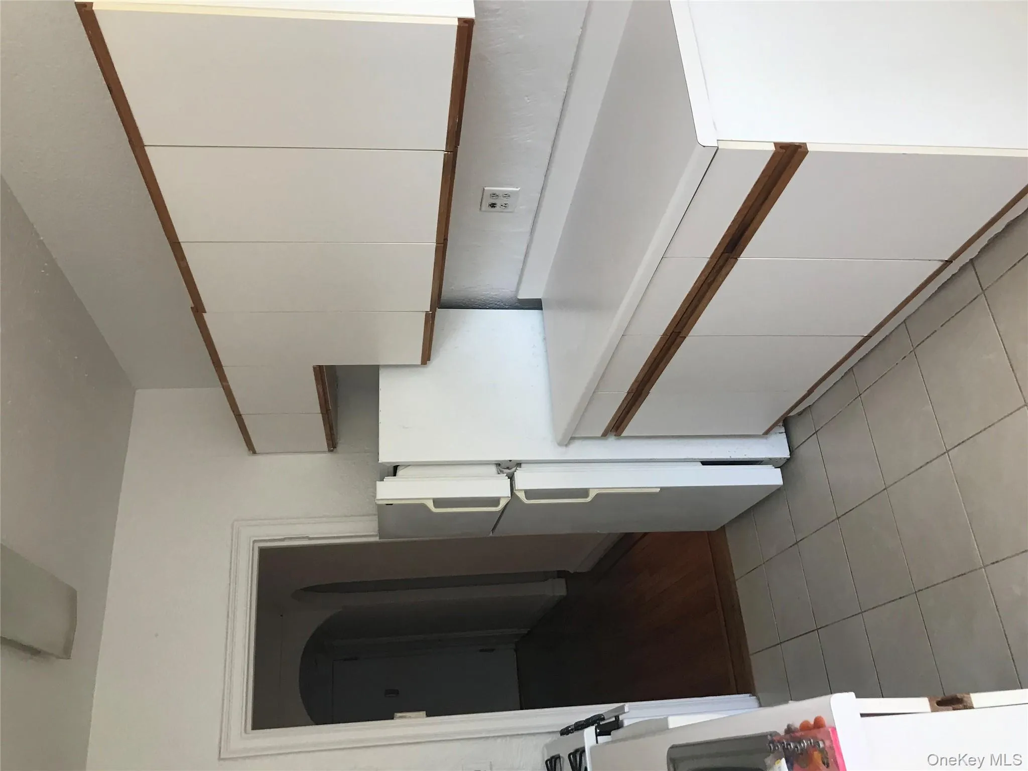 Kitchen with white cabinetry, light countertops, freestanding refrigerator, arched walkways, and light tile patterned flooring Kitchen with white cabinetry, light countertops, freestanding refrigerator, arched walkways, and light tile patterned flooring