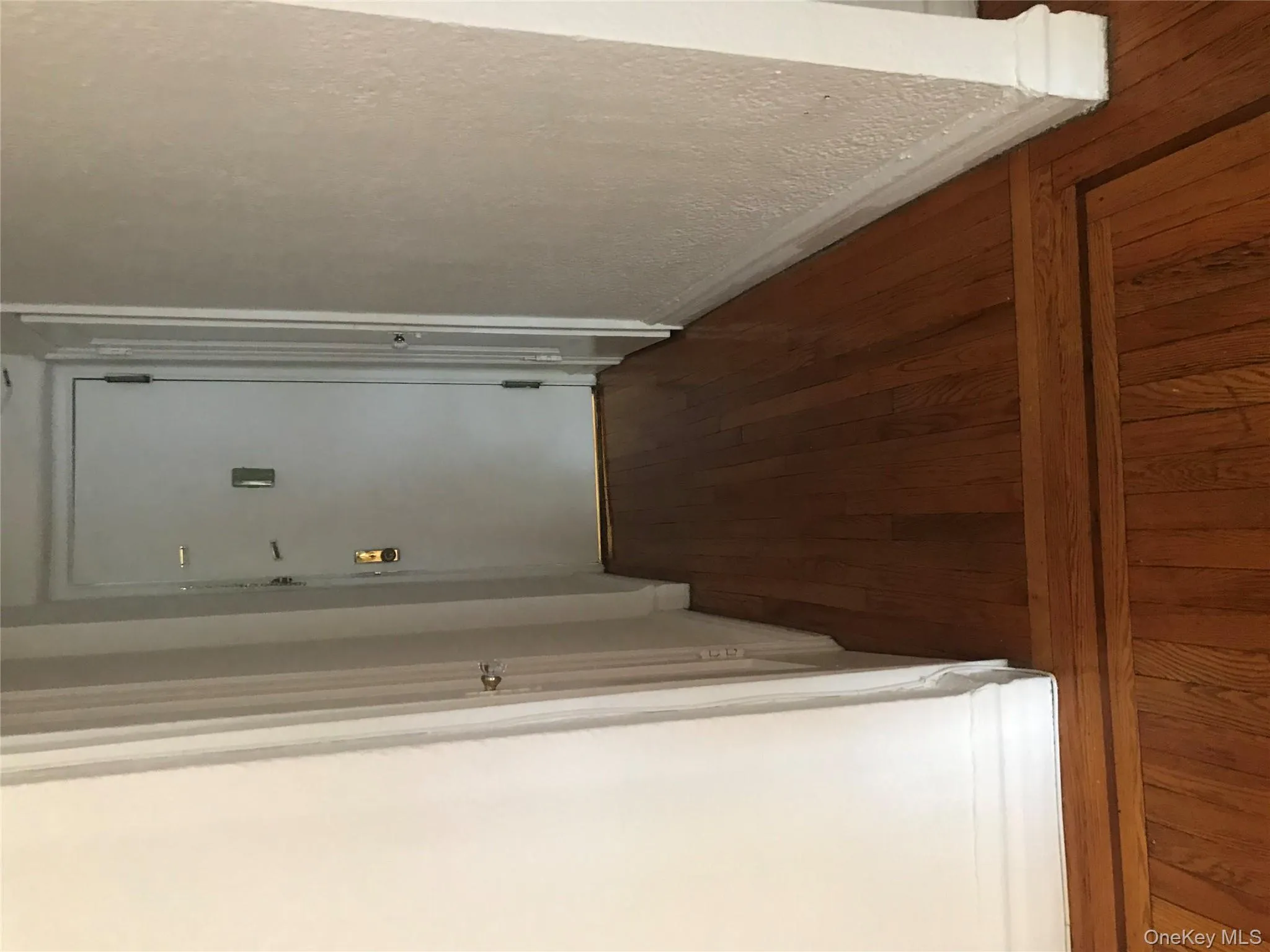 Hall featuring dark wood-style floors and a textured wall Hall featuring dark wood-style floors and a textured wall