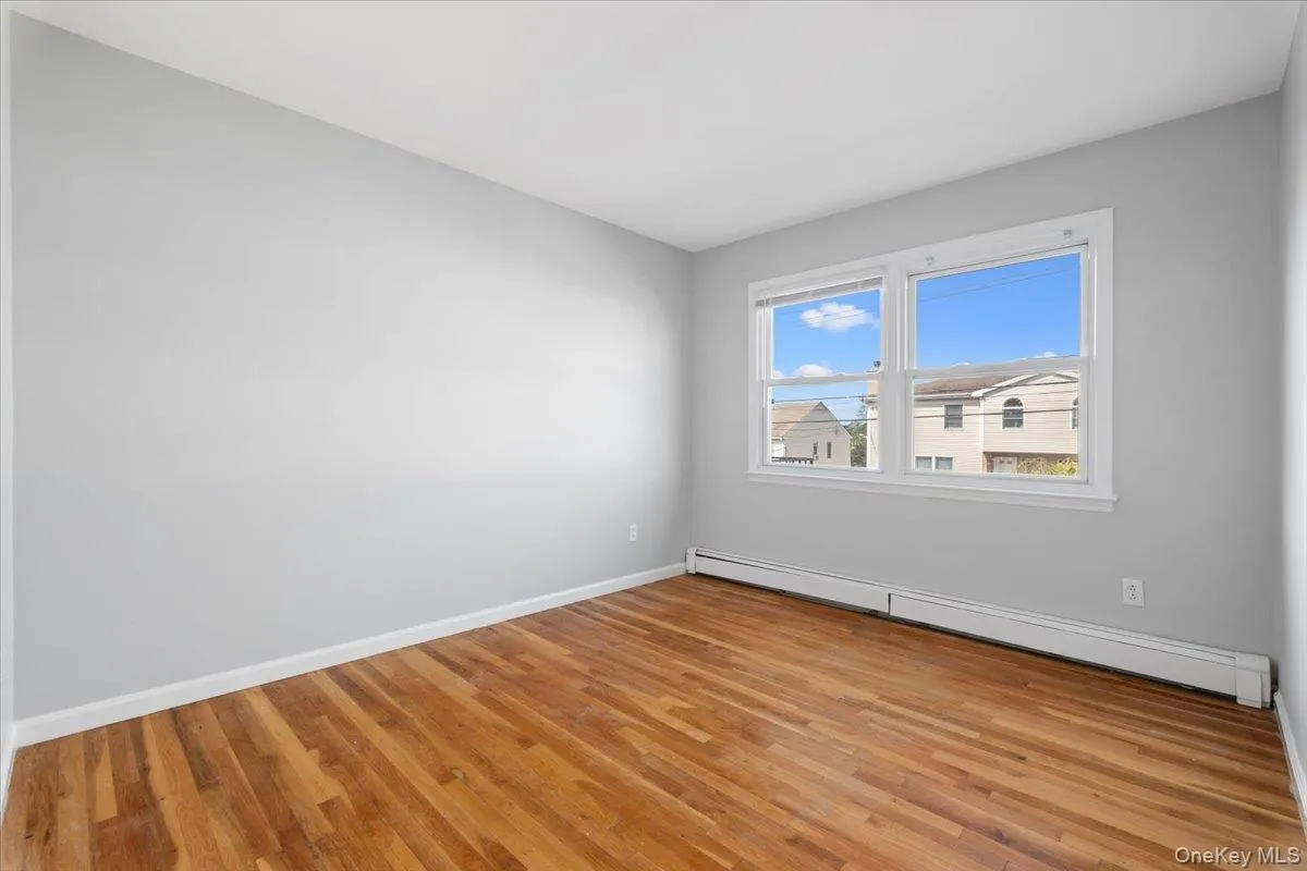 Spare room with a baseboard heating unit and light wood finished floors Spare room with a baseboard heating unit and light wood finished floors