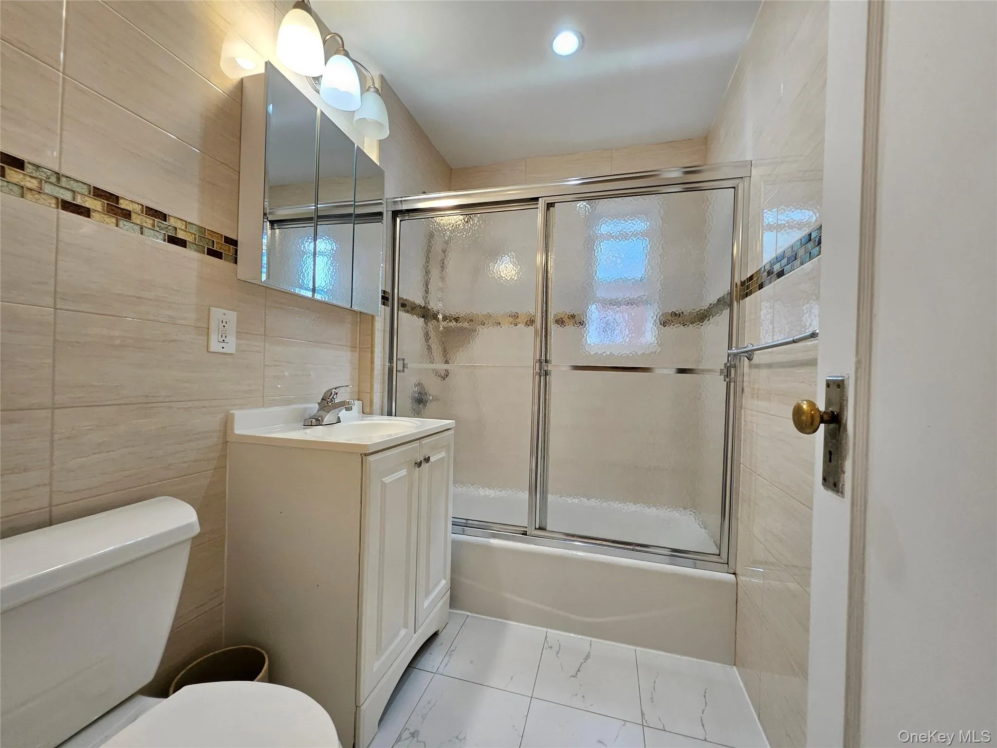 Bathroom featuring enclosed tub / shower combo, vanity, and tile walls Bathroom featuring enclosed tub / shower combo, vanity, and tile walls