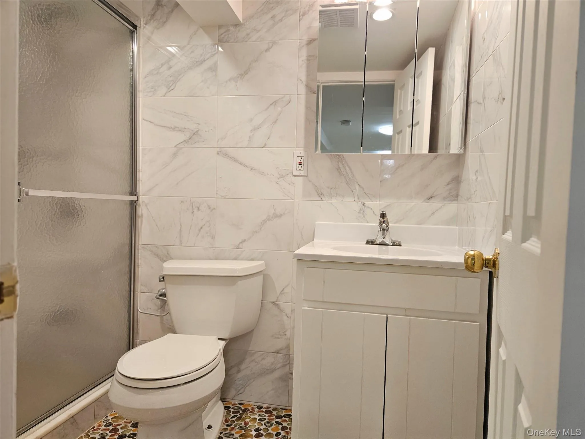 Full bathroom featuring tile walls, vanity, a shower stall, and tile patterned flooring Full bathroom featuring tile walls, vanity, a shower stall, and tile patterned flooring