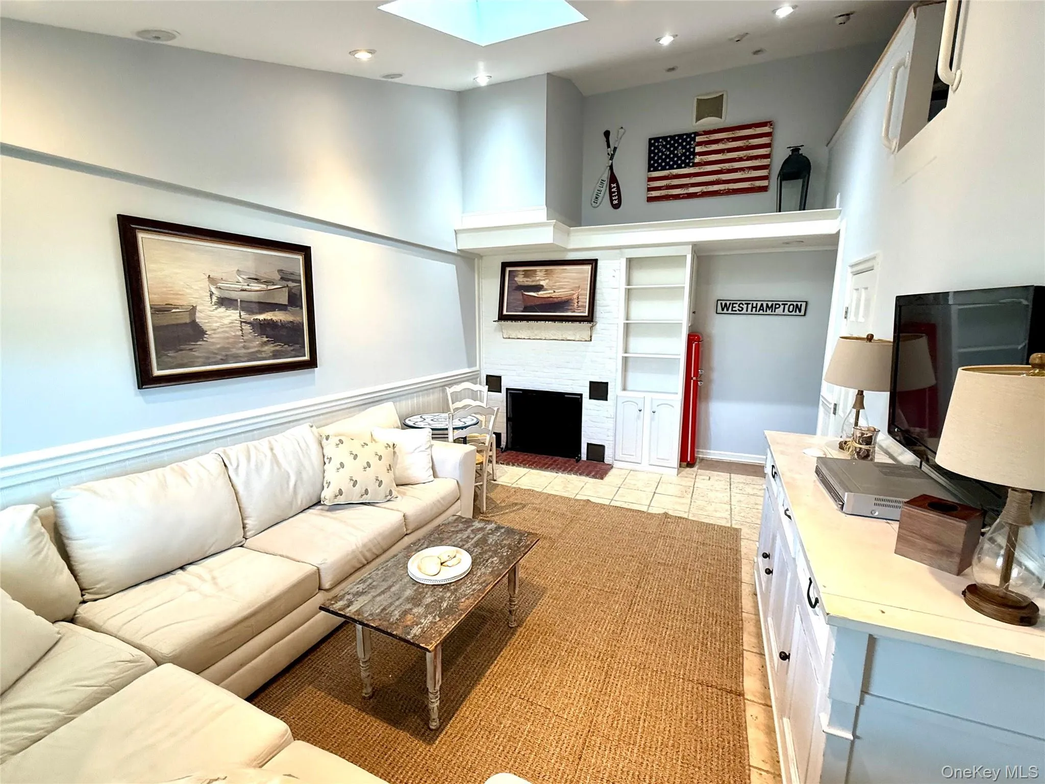 Living area with a skylight, recessed lighting, a fireplace with raised hearth, a high ceiling, and light tile patterned floors Living area with a skylight, recessed lighting, a fireplace with raised hearth, a high ceiling, and light tile patterned floors