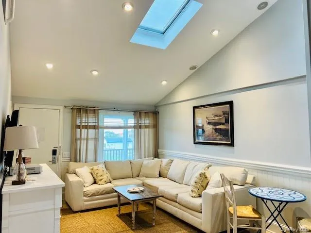 Living room featuring vaulted ceiling, recessed lighting, a skylight, and a wainscoted wall Living room featuring vaulted ceiling, recessed lighting, a skylight, and a wainscoted wall
