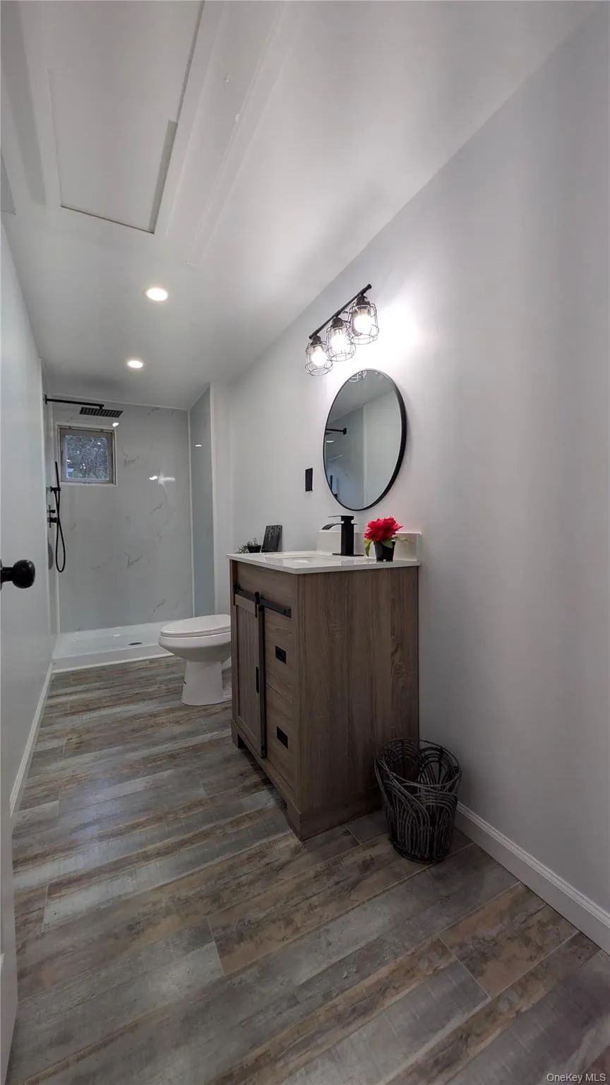 Full bathroom featuring a stall shower, vanity, light wood-style floors, and recessed lighting Full bathroom featuring a stall shower, vanity, light wood-style floors, and recessed lighting