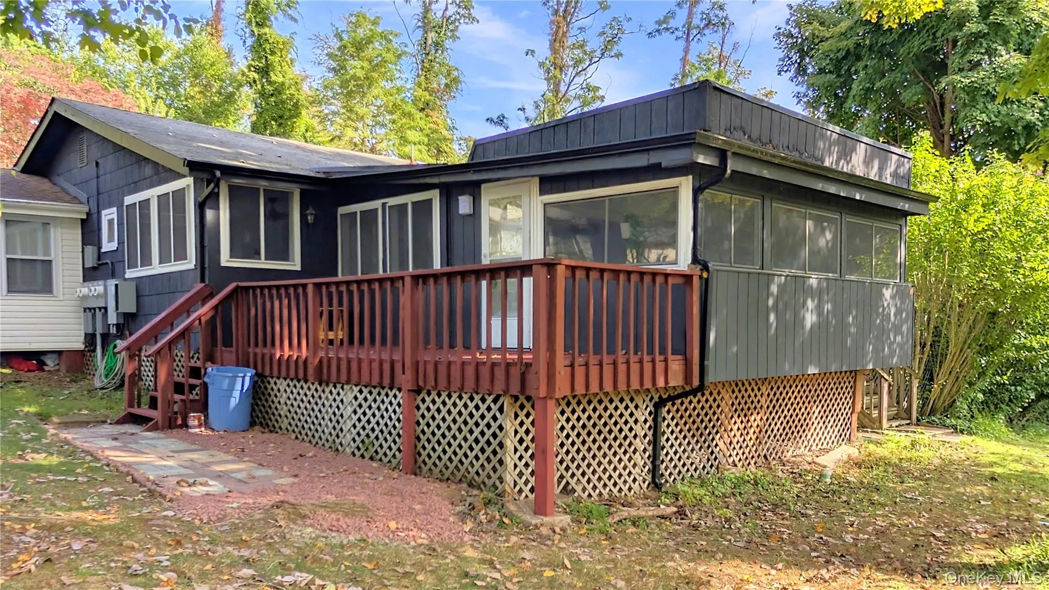 Back of house with a sunroom and a wooden deck Back of house with a sunroom and a wooden deck