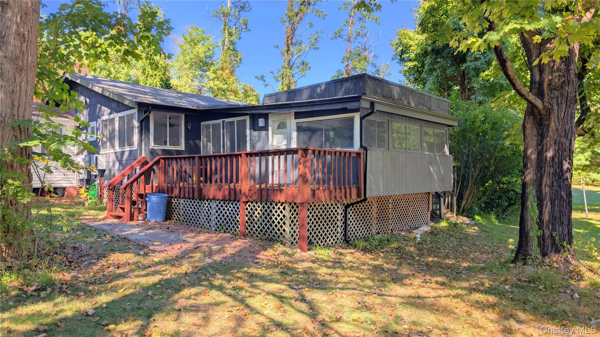 Rear view of house featuring a sunroom and a wooden deck Rear view of house featuring a sunroom and a wooden deck