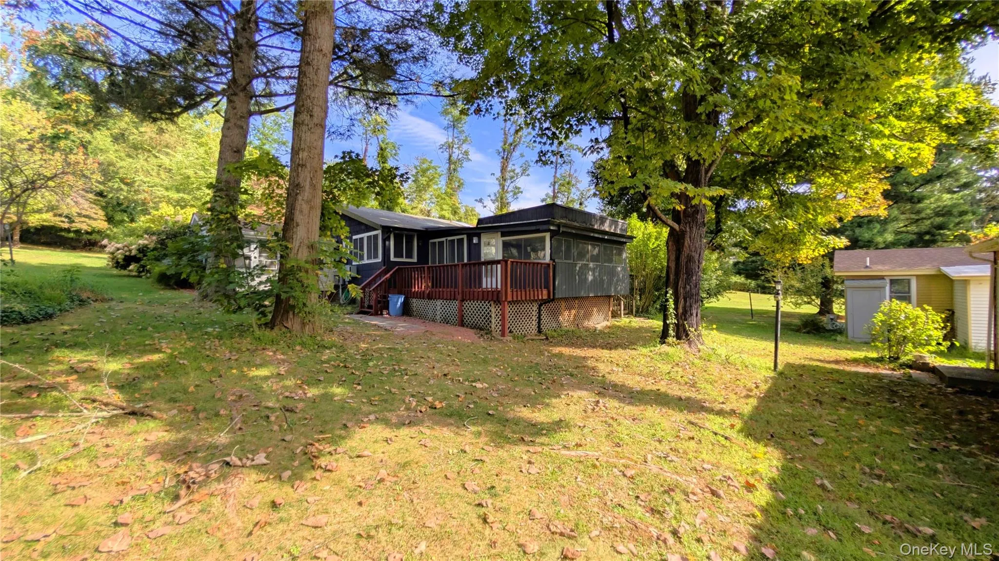 View of grassy yard featuring a sunroom and a deck View of grassy yard featuring a sunroom and a deck