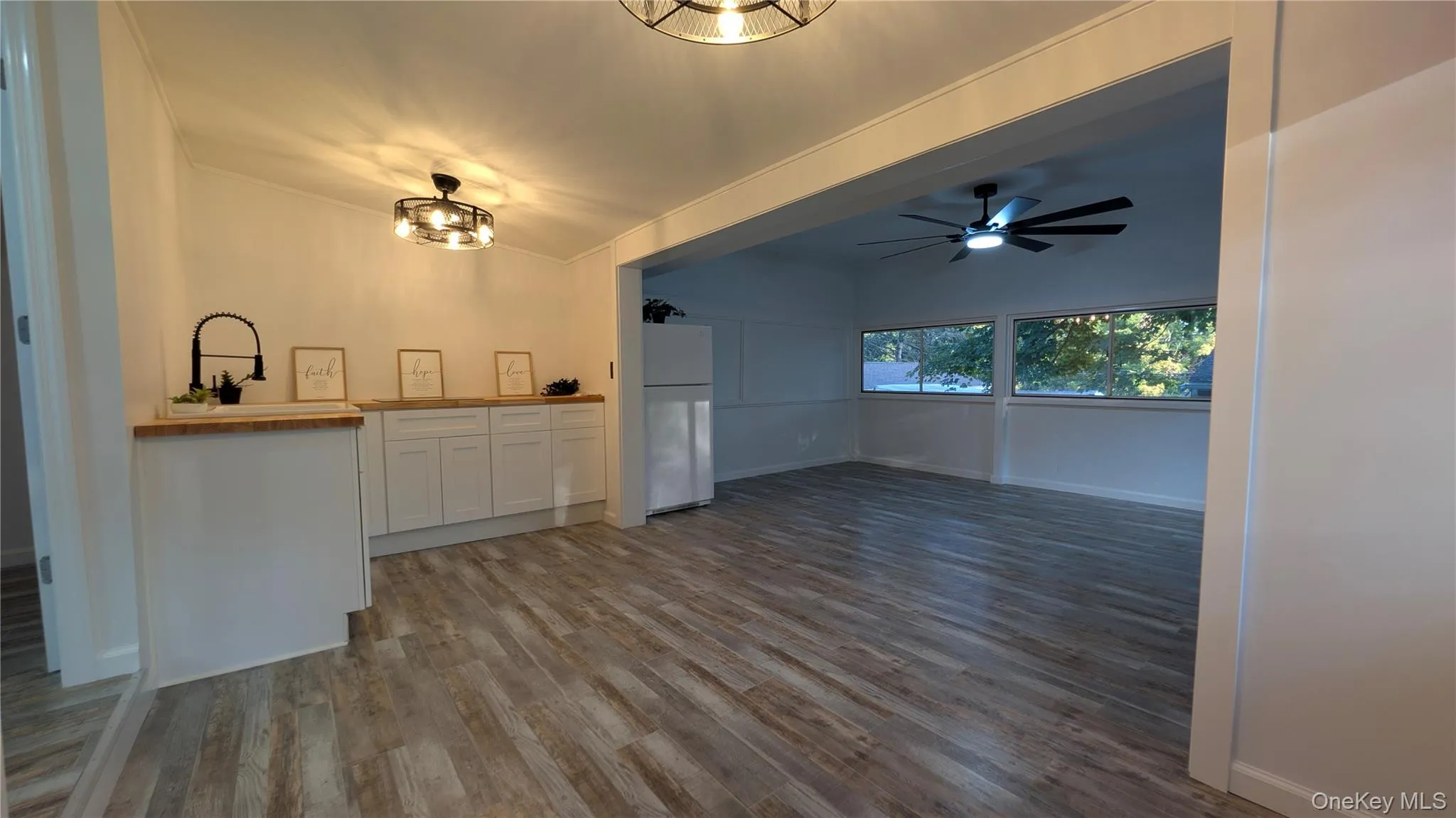 Kitchen featuring white cabinets, freestanding refrigerator, wood counters, wood finished floors, and a ceiling fan Kitchen featuring white cabinets, freestanding refrigerator, wood counters, wood finished floors, and a ceiling fan