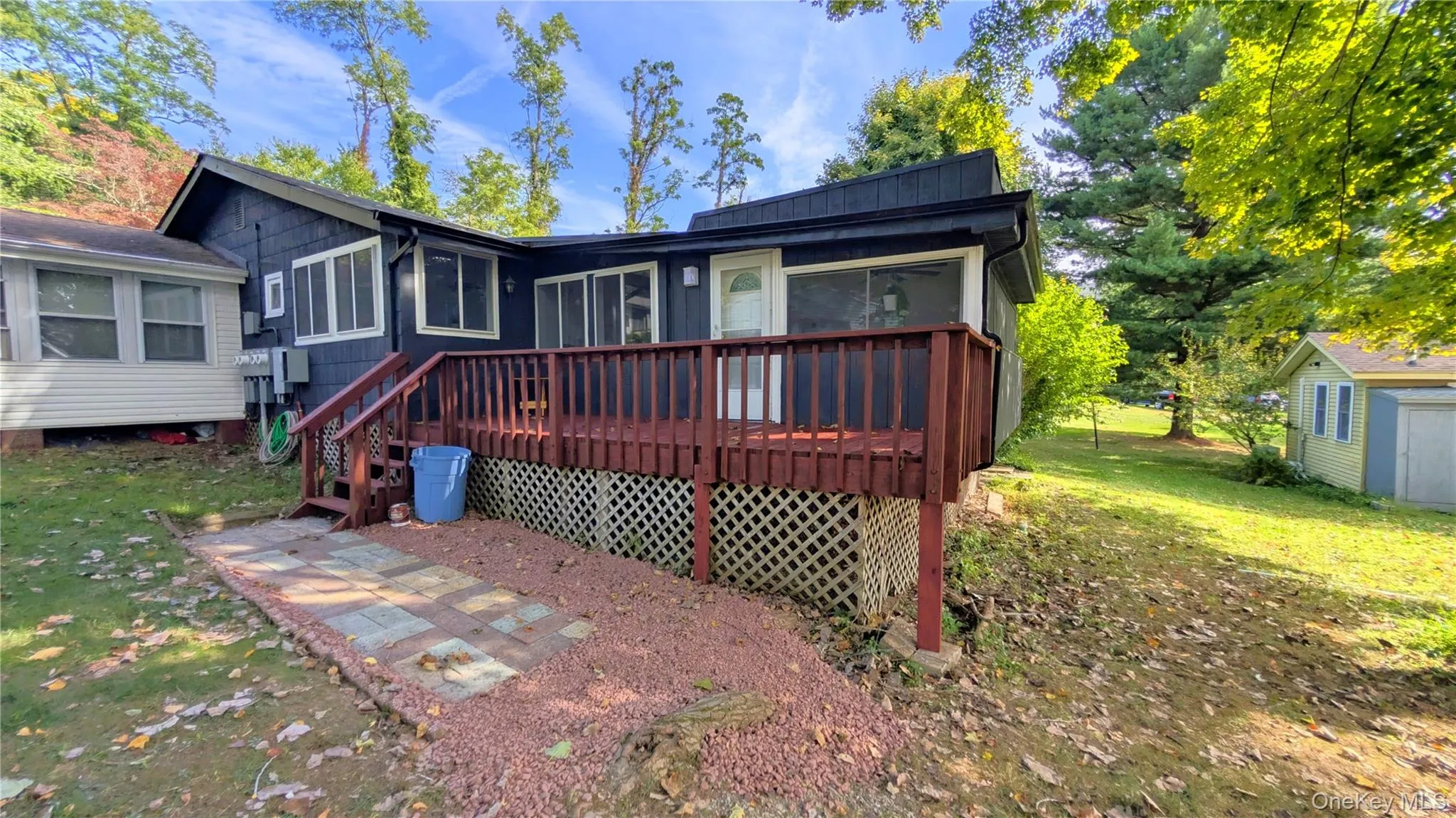 Rear view of house featuring a wooden deck, a sunroom, and a lawn Rear view of house featuring a wooden deck, a sunroom, and a lawn