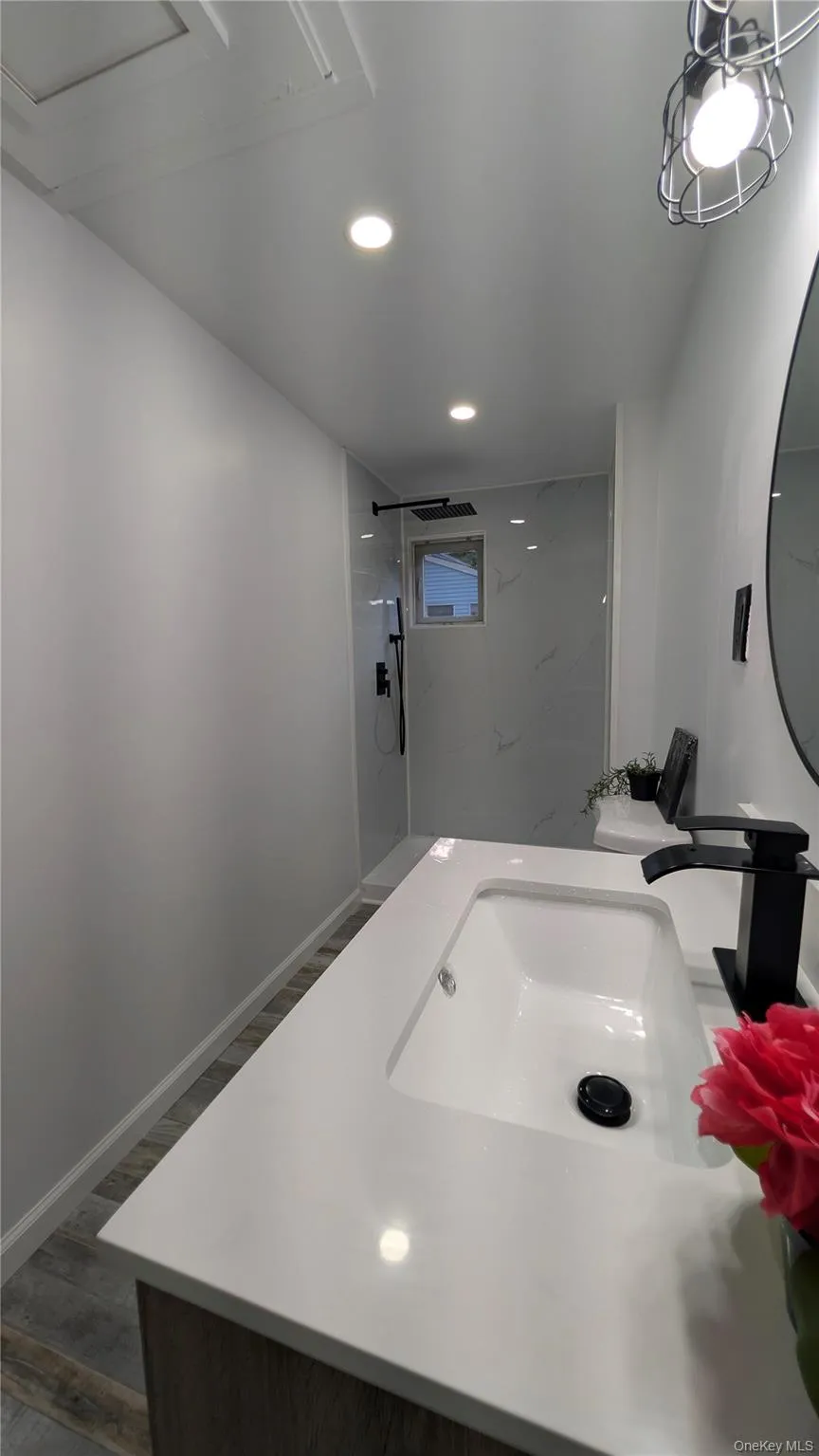 Full bathroom with a marble finish shower, recessed lighting, wood finished floors, and vanity Full bathroom with a marble finish shower, recessed lighting, wood finished floors, and vanity
