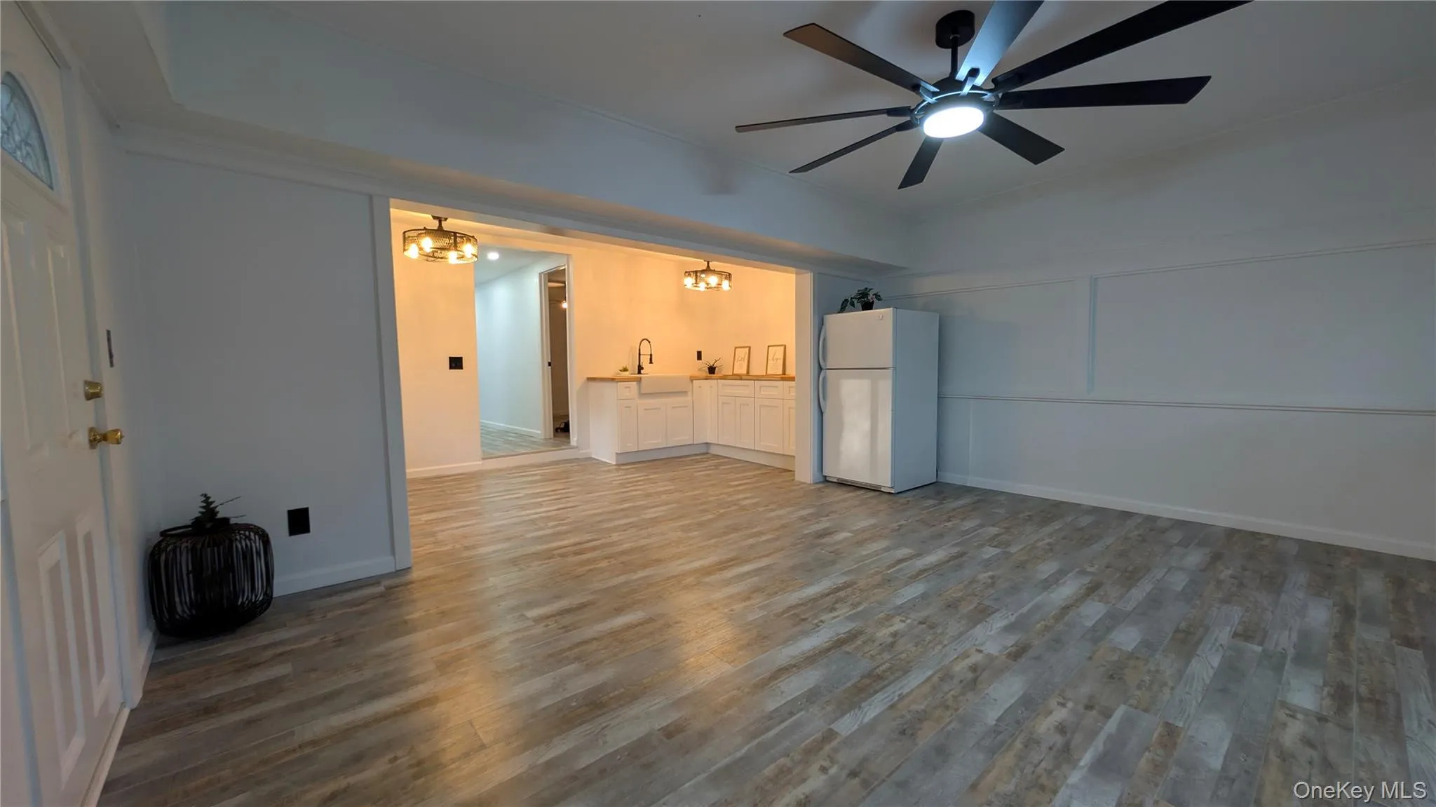 Unfurnished living room featuring wood finished floors, a chandelier, ornamental molding, and ceiling fan Unfurnished living room featuring wood finished floors, a chandelier, ornamental molding, and ceiling fan