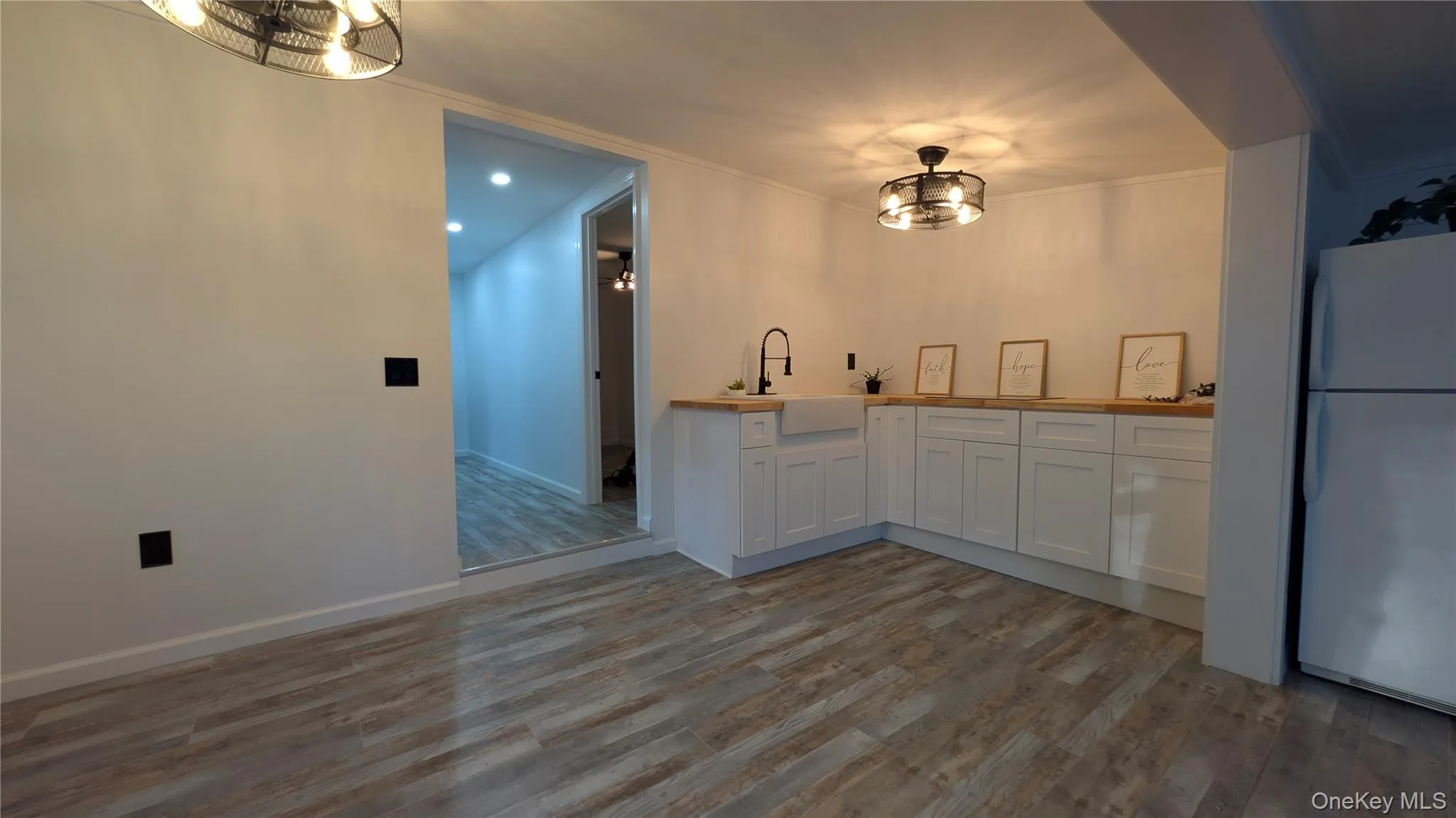 Kitchen with freestanding refrigerator, white cabinets, wood counters, dark wood-type flooring, and recessed lighting Kitchen with freestanding refrigerator, white cabinets, wood counters, dark wood-type flooring, and recessed lighting