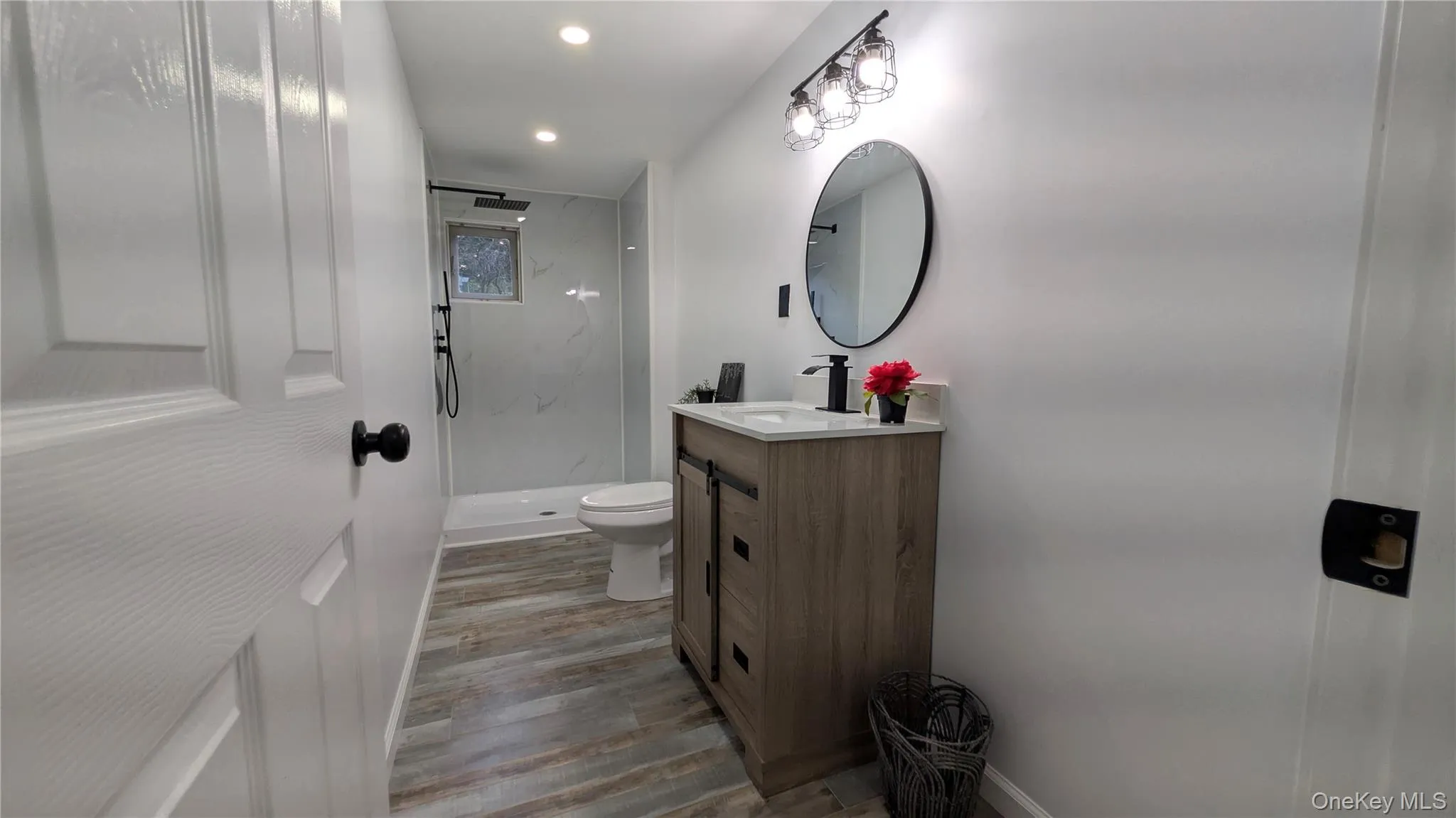 Full bathroom featuring a marble finish shower, vanity, light wood-style flooring, and recessed lighting Full bathroom featuring a marble finish shower, vanity, light wood-style flooring, and recessed lighting