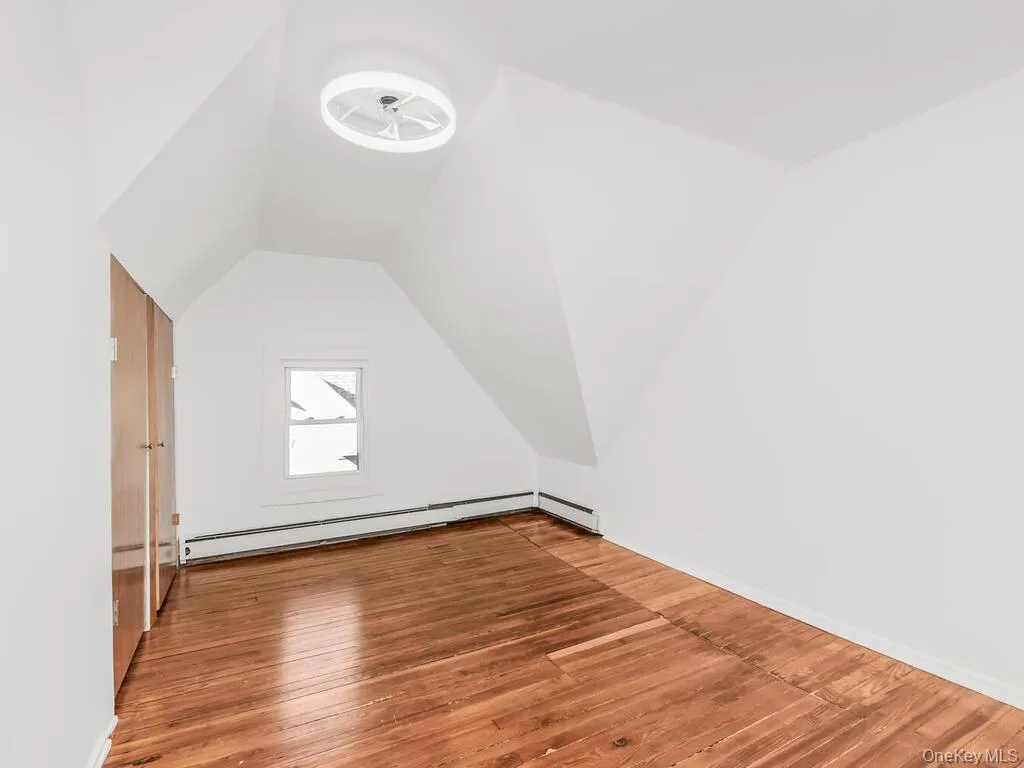 Additional living space featuring hardwood / wood-style floors, lofted ceiling, and baseboard heating Additional living space featuring hardwood / wood-style floors, lofted ceiling, and baseboard heating