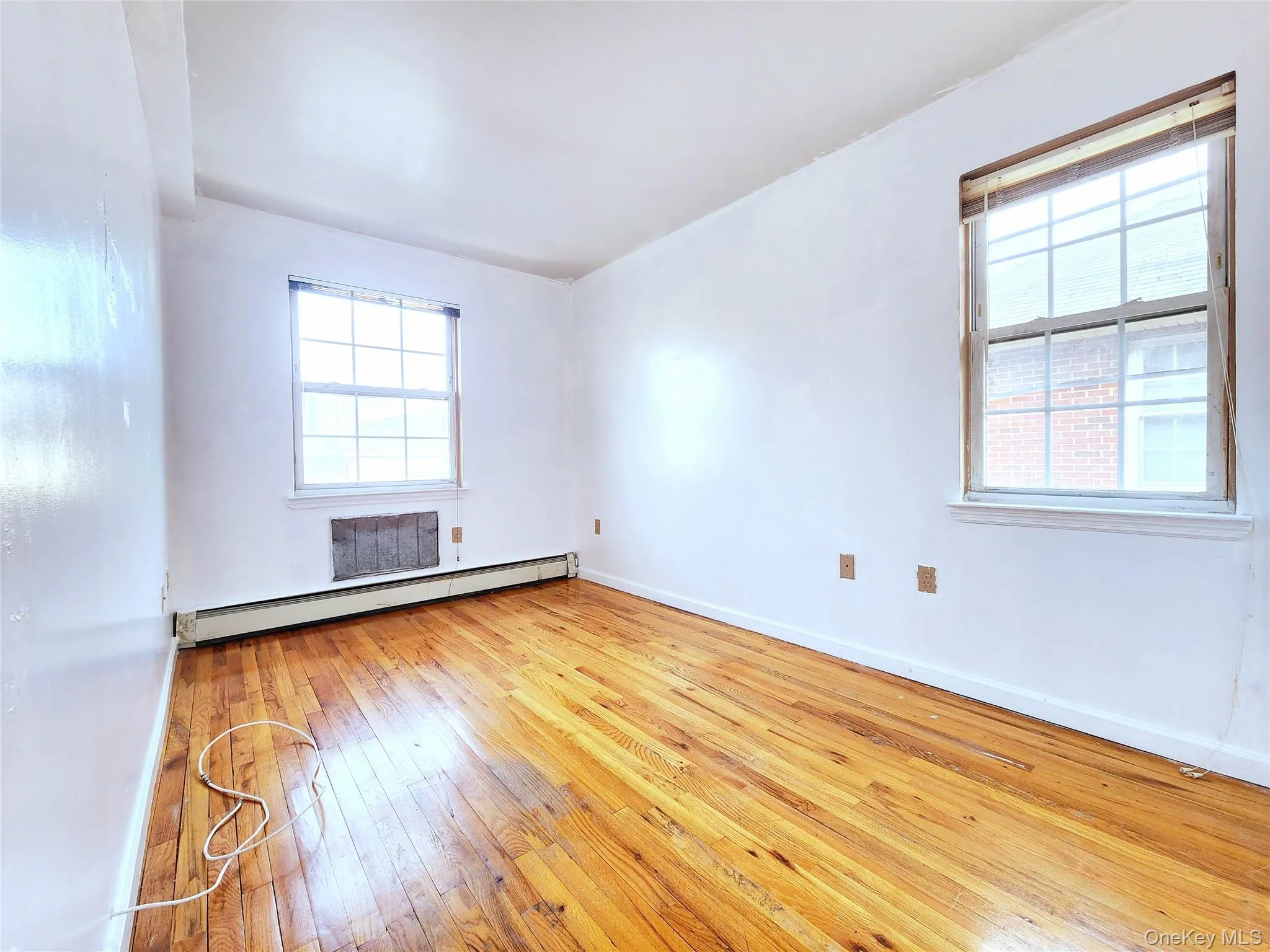 Empty room featuring light wood-type flooring, healthy amount of natural light, and baseboard heating Empty room featuring light wood-type flooring, healthy amount of natural light, and baseboard heating