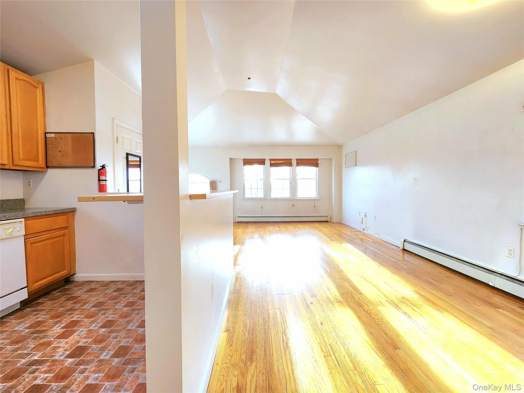 Unfurnished living room with vaulted ceiling and baseboard heating Unfurnished living room with vaulted ceiling and baseboard heating