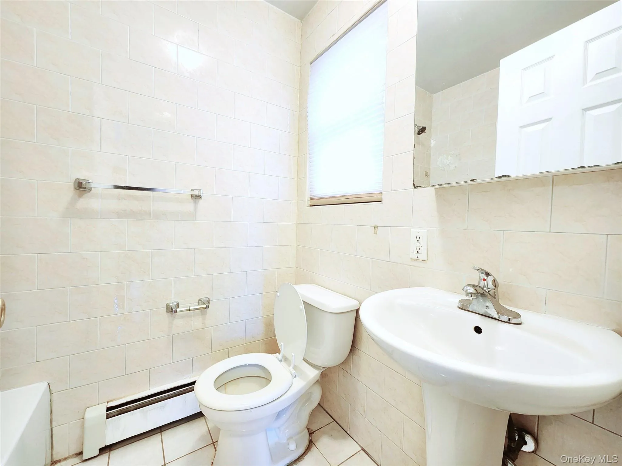 Full bathroom featuring a baseboard heating unit, tile walls, and tile patterned floors Full bathroom featuring a baseboard heating unit, tile walls, and tile patterned floors