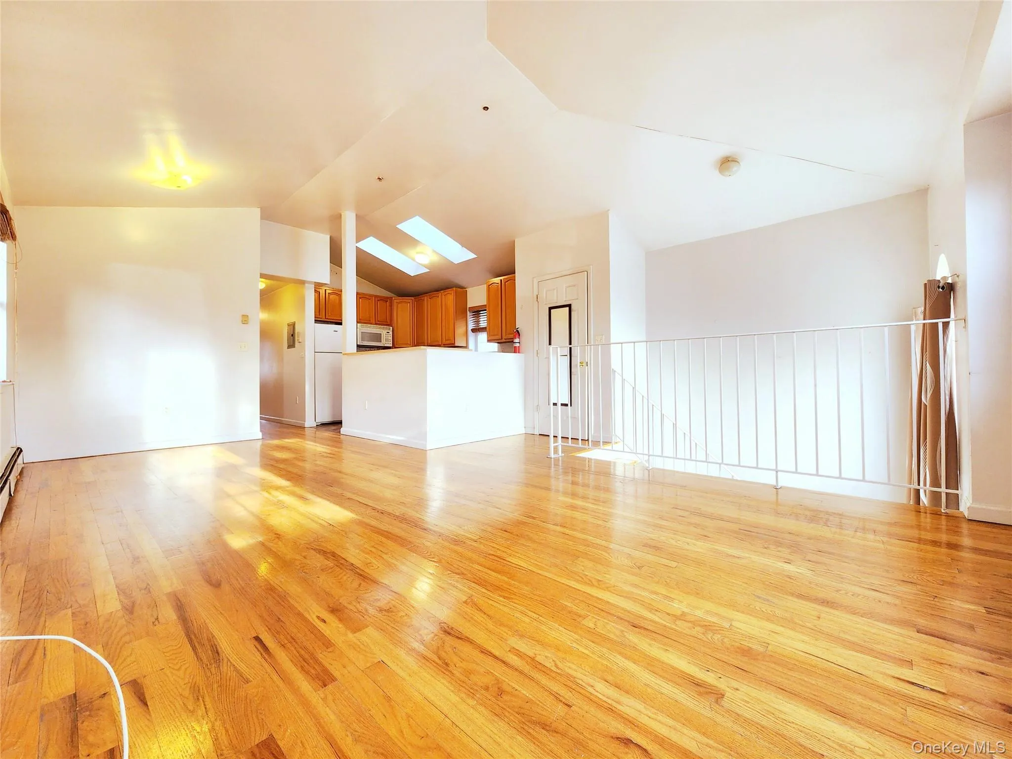 Unfurnished living room featuring light wood-type flooring, lofted ceiling, and a skylight Unfurnished living room featuring light wood-type flooring, lofted ceiling, and a skylight