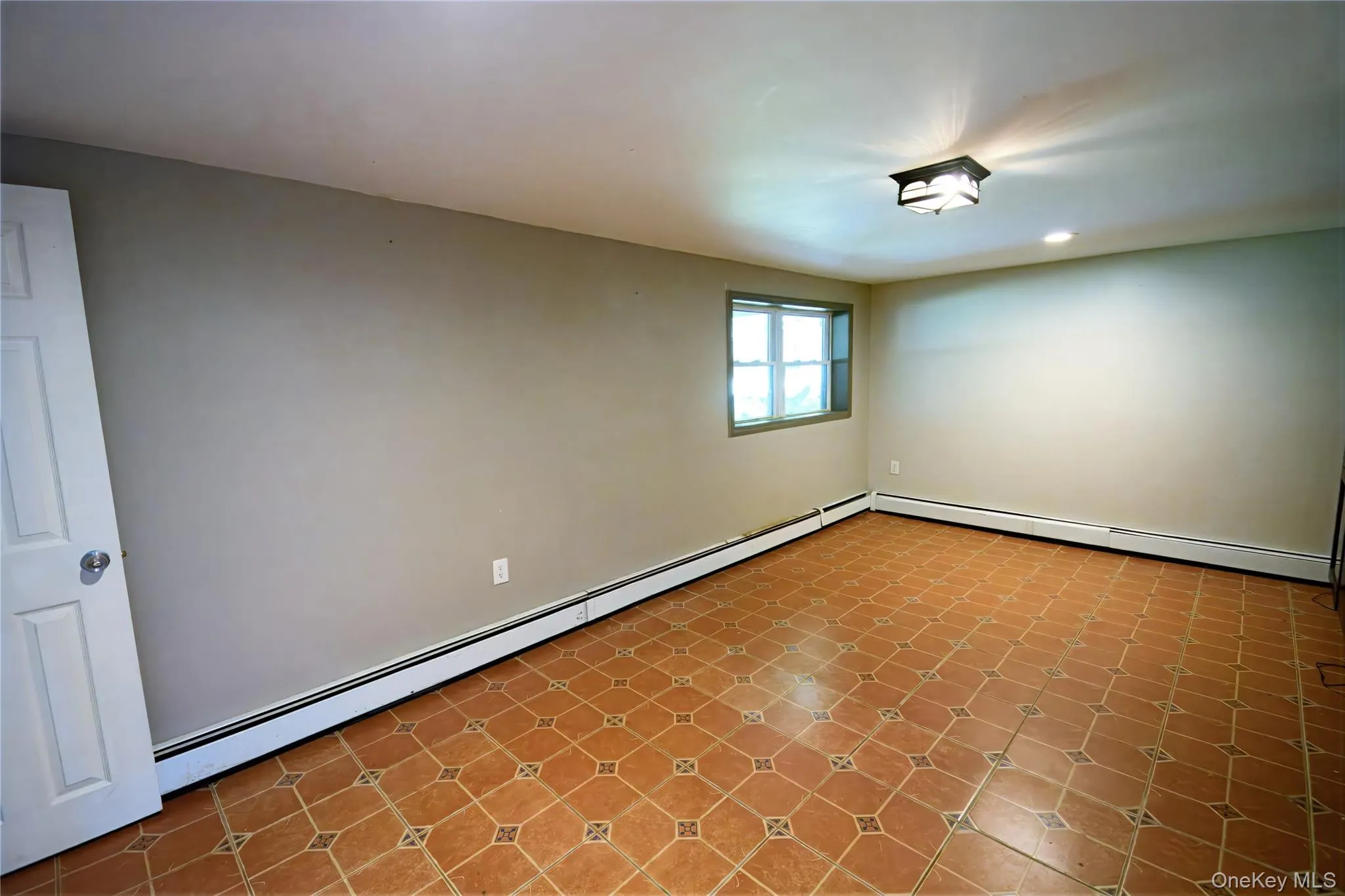 Empty room with a baseboard radiator and light tile patterned flooring Empty room with a baseboard radiator and light tile patterned flooring