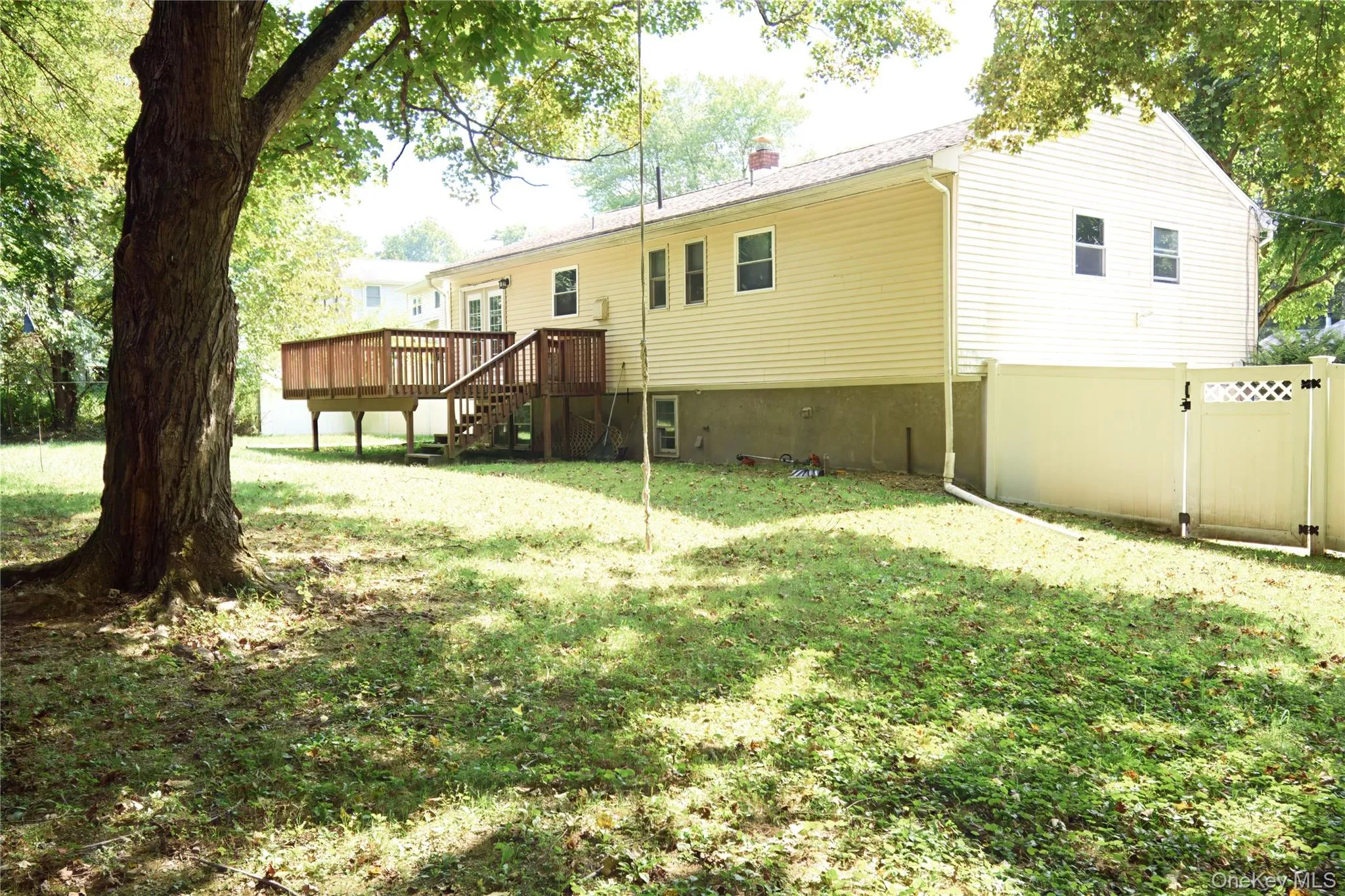Back of property featuring a wooden deck, a gate, a chimney, and stairs Back of property featuring a wooden deck, a gate, a chimney, and stairs
