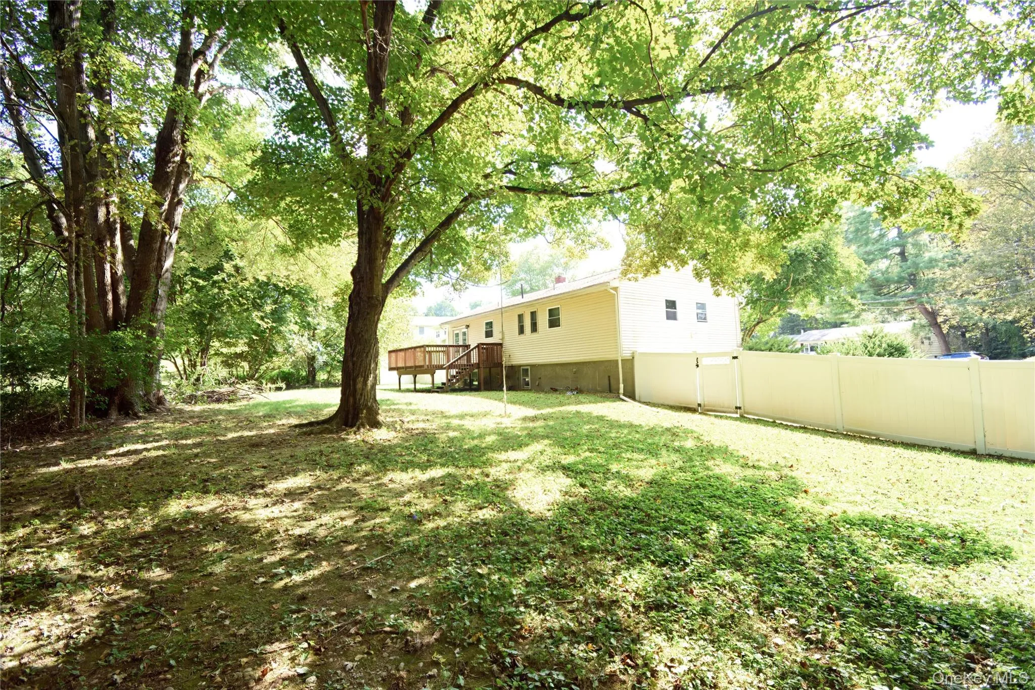 View of yard featuring a wooden deck, a gate, and view of scattered trees View of yard featuring a wooden deck, a gate, and view of scattered trees