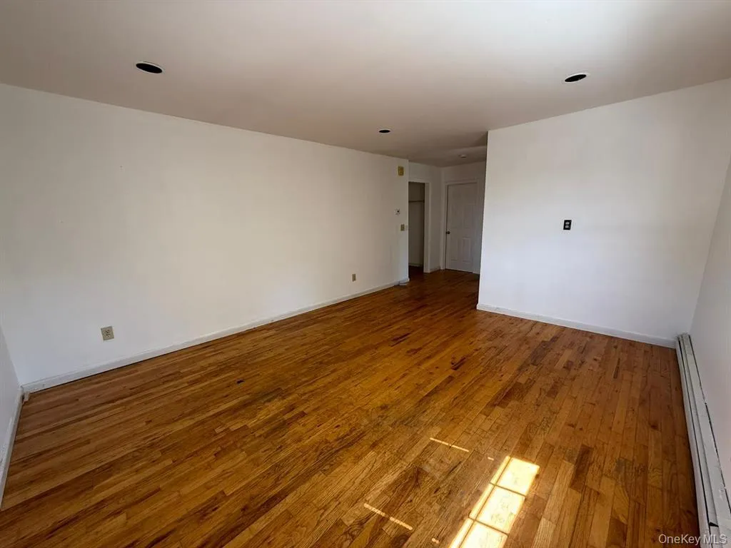 Spare room with a baseboard radiator and hardwood / wood-style floors Spare room with a baseboard radiator and hardwood / wood-style floors